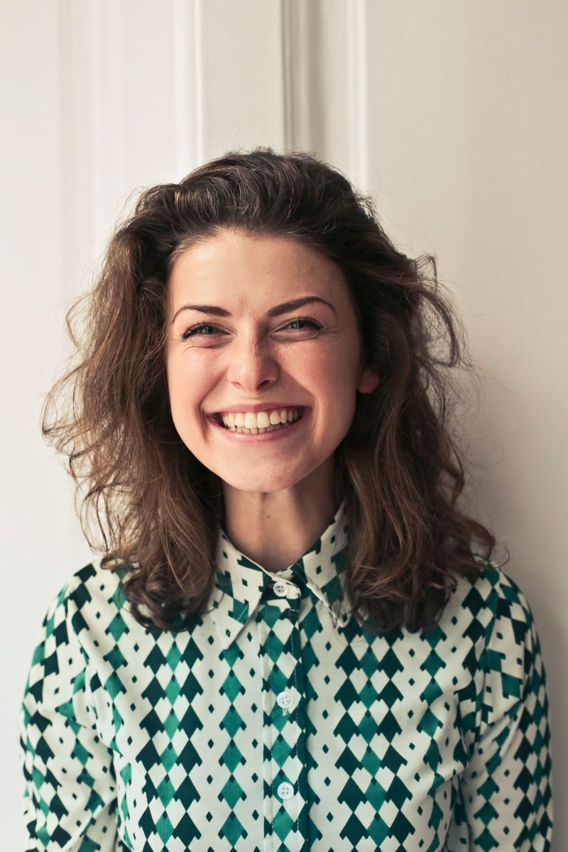 Portrait of Elin Fielden smiling against a pale wall