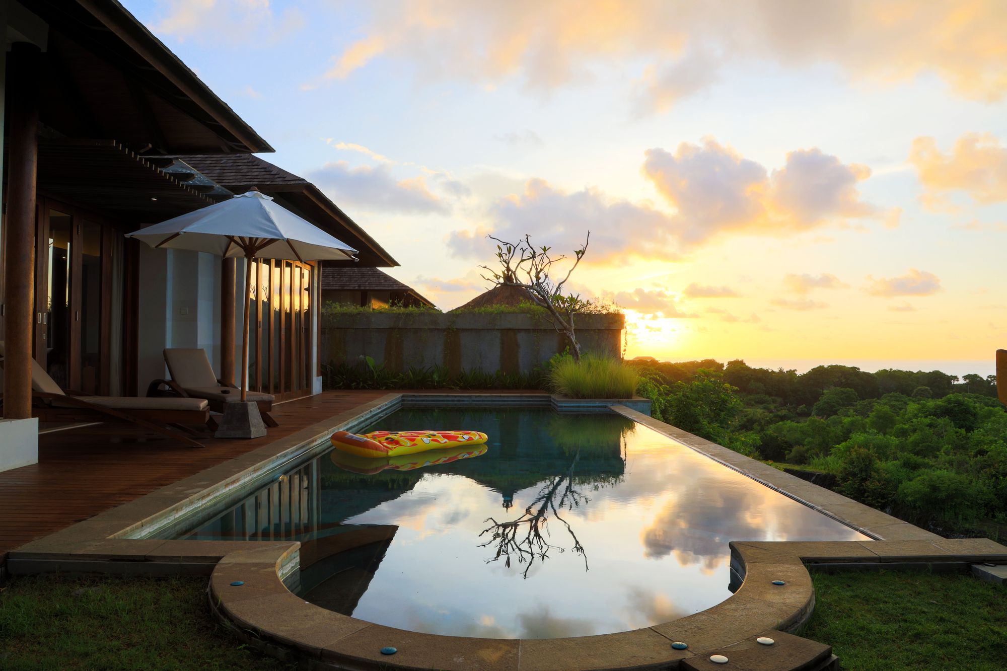 Exterior render of a tropical villa with a mirror-still infinity pool at golden hour