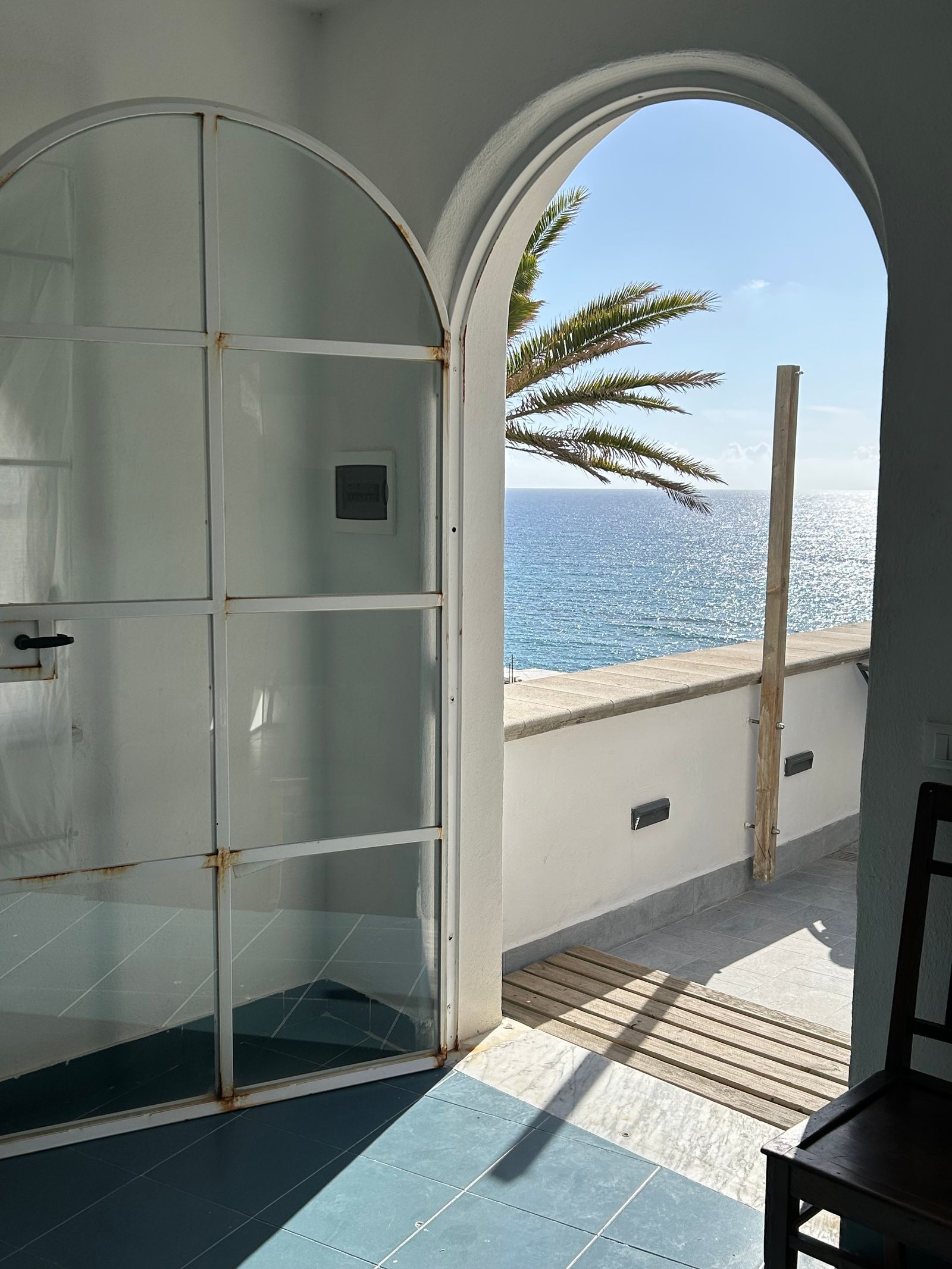 Interior render framing the sea through a tall arched terrace doorway