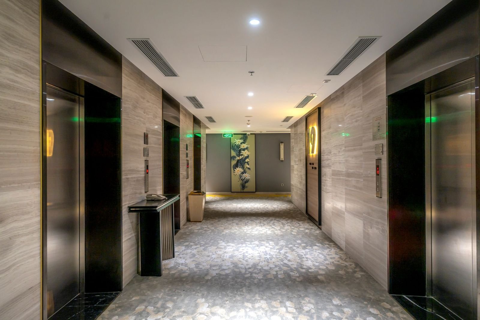 A quiet hotel corridor receding toward a lift lobby