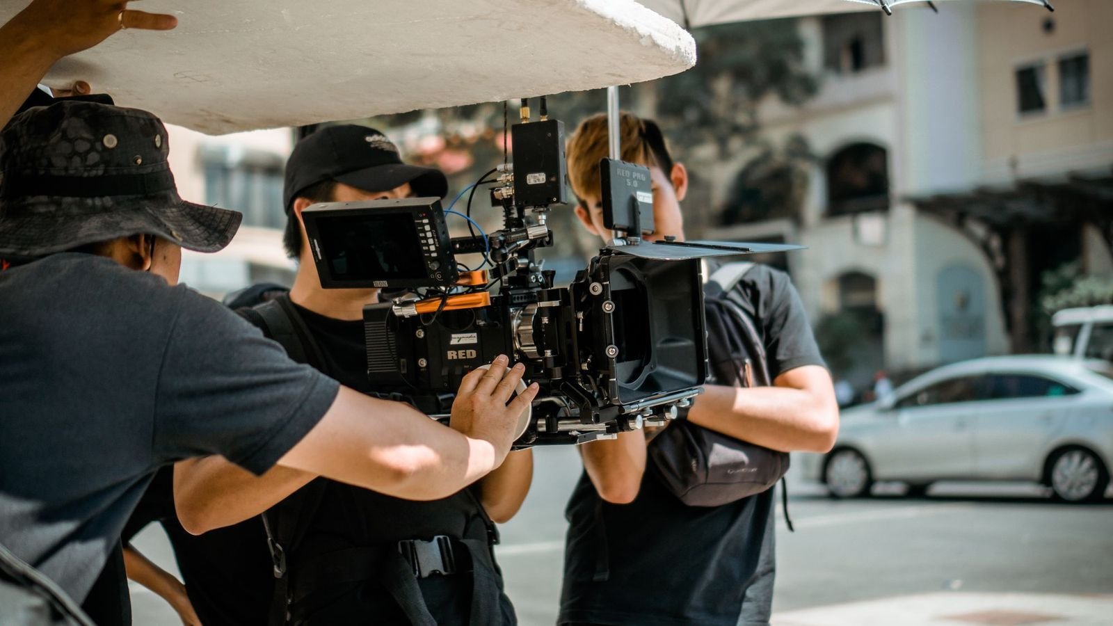 A film crew working a cinema camera on a city pavement