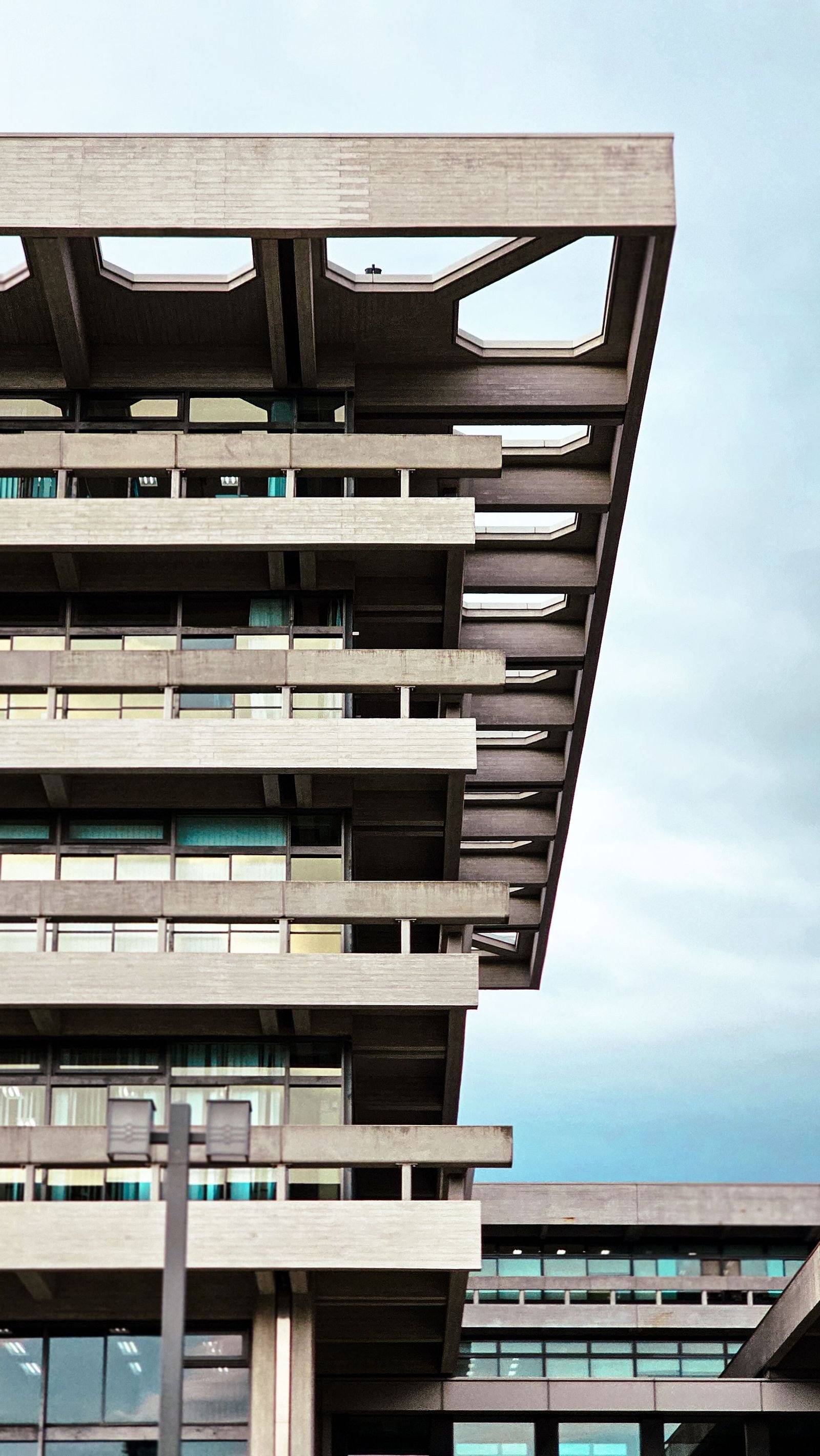 Geometric brutalist rooflines cutting against a bright, empty sky