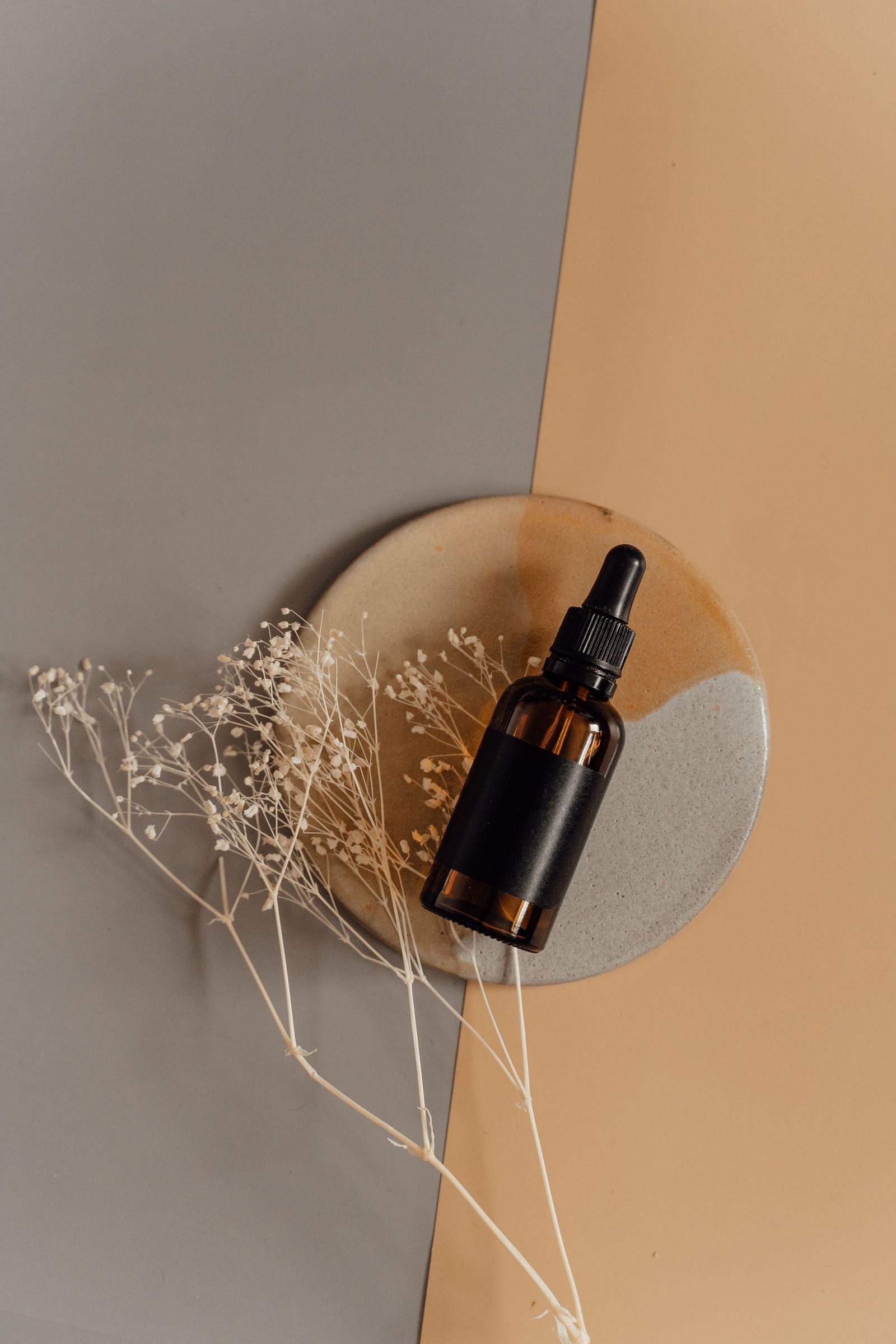 A single amber dropper bottle styled against a warm neutral ground