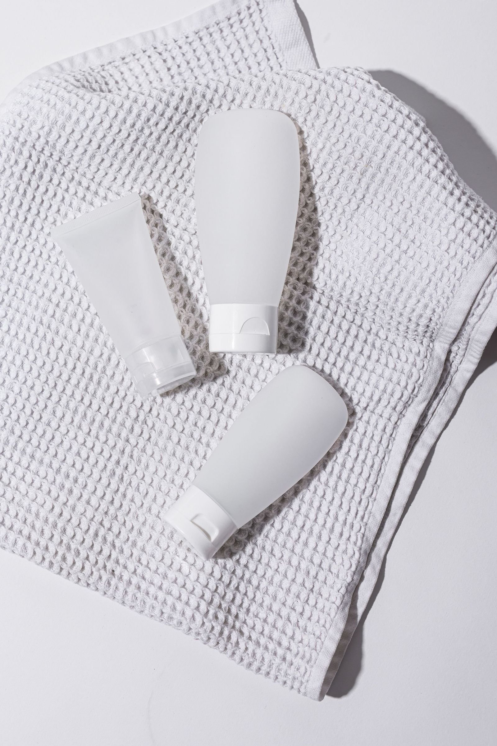 Three unlabelled white tubes lying on a heavy linen cloth
