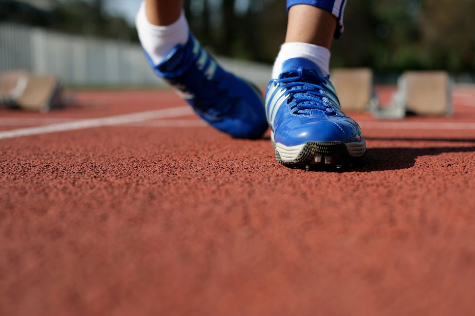 A runner's shoes on a synthetic track, laced and set at the line