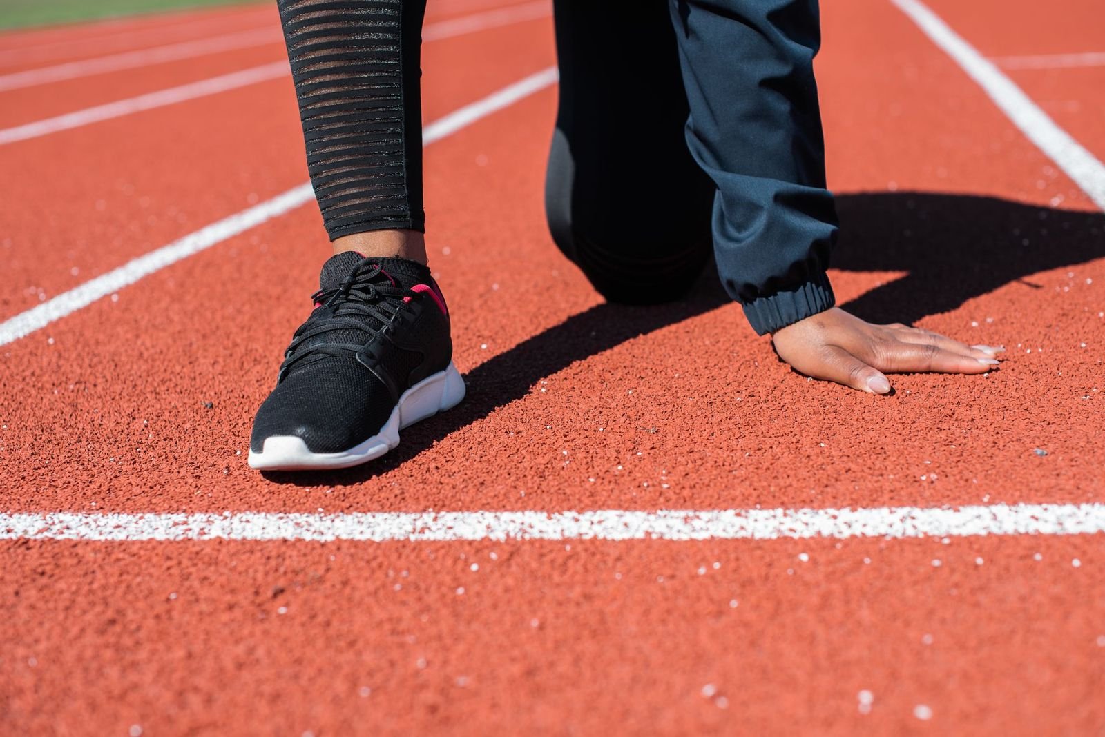A sprinter set in the blocks on an outdoor track, seen from the side
