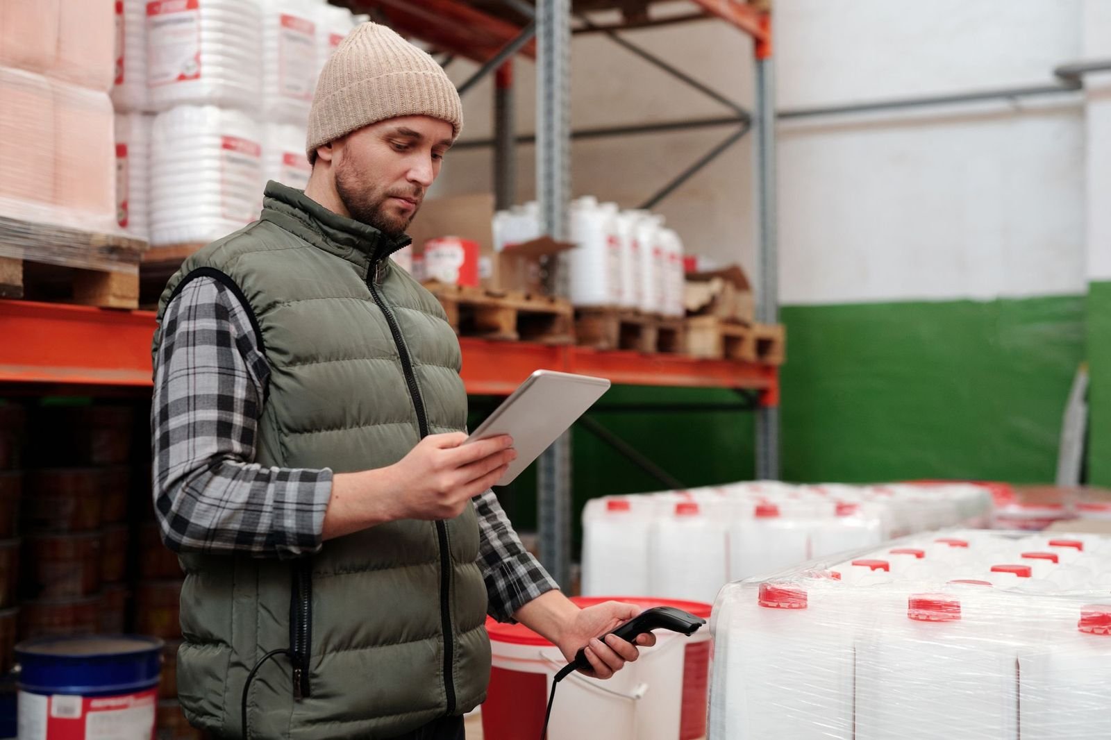 A warehouse operator checking stock against a tablet between racking