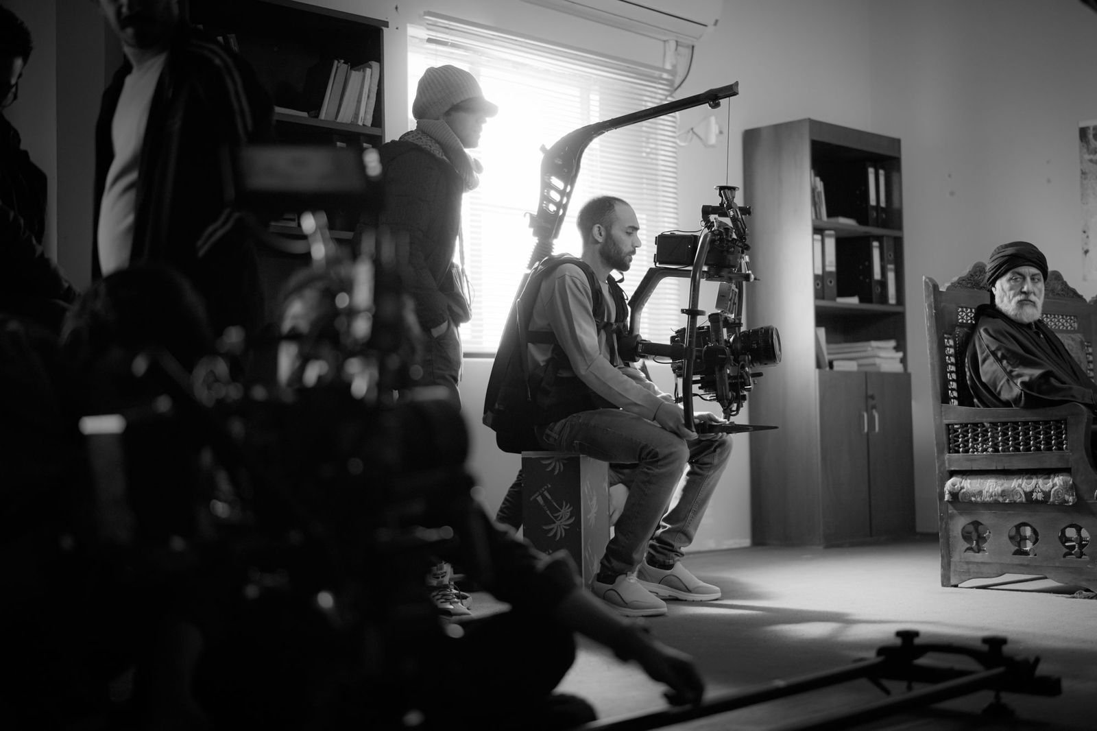 Black and white frame of a crew working around camera equipment