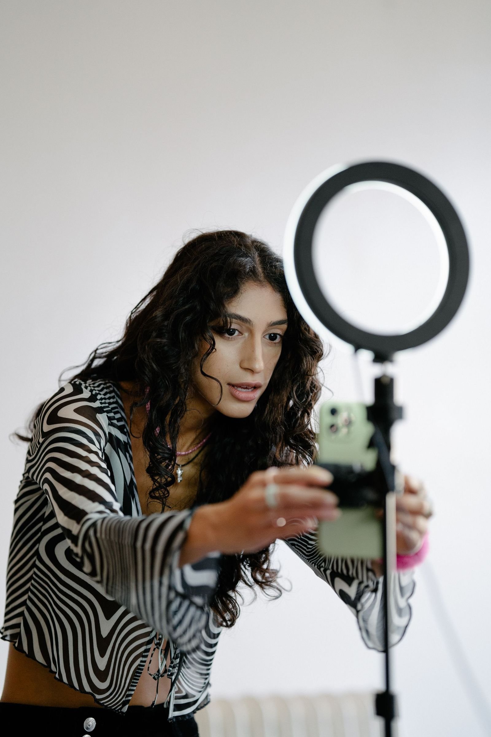 A phone on a tripod under a ring light, set up to record