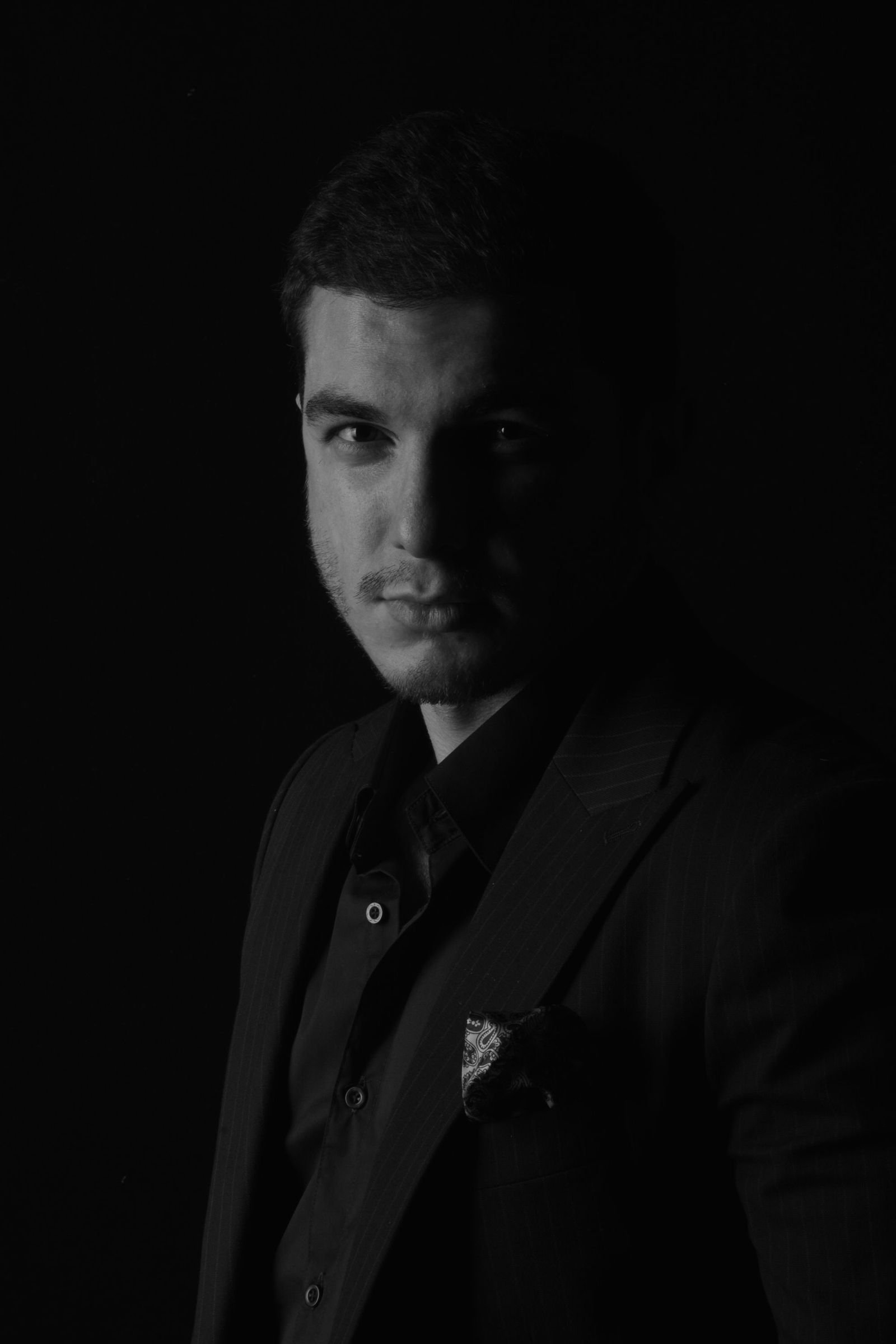 Studio portrait against a dark ground, side-lit