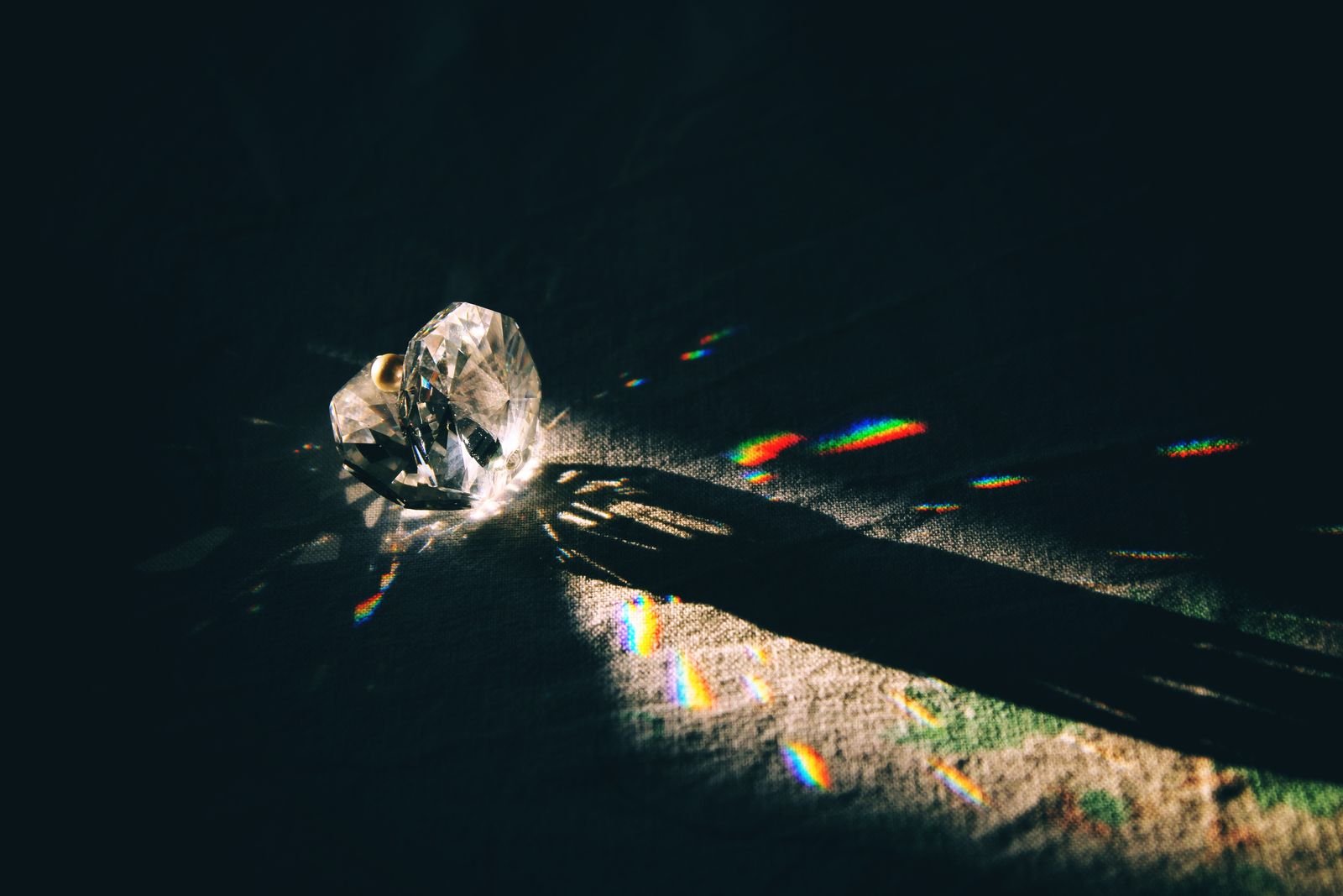 A cut crystal throwing rainbow reflections across a dark surface
