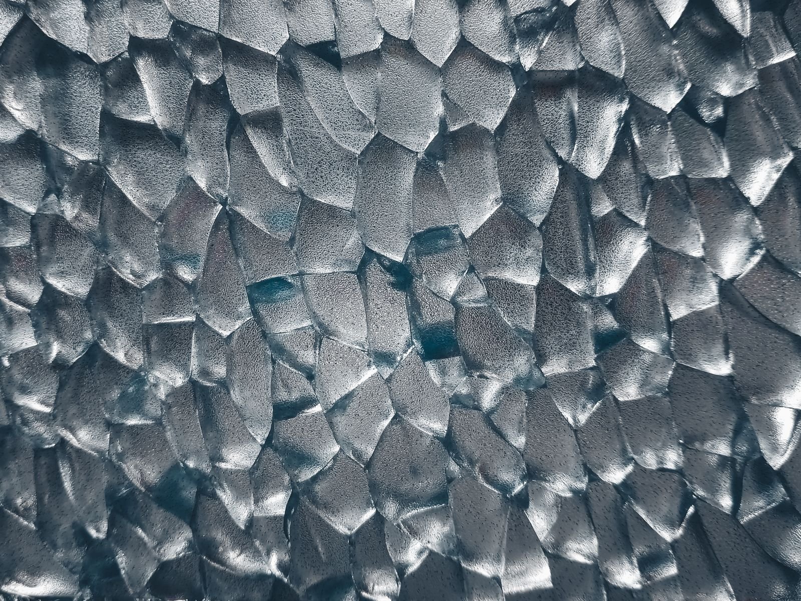 A macro texture of fractured glass catching cold light