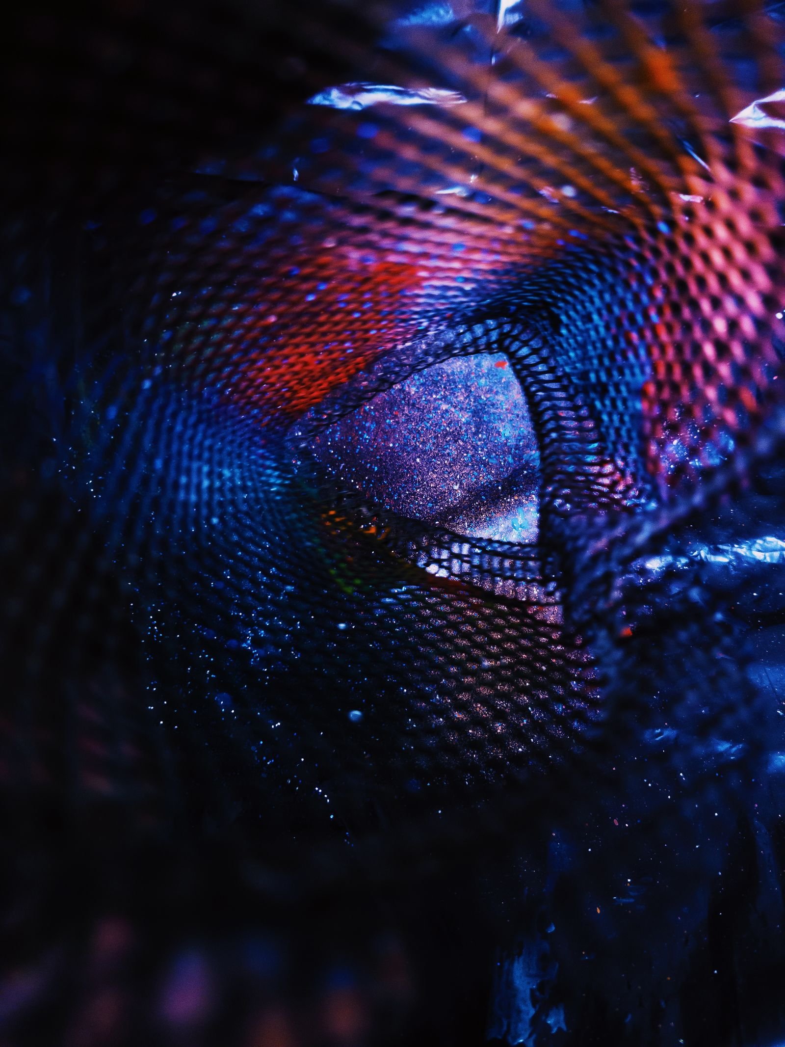 Iridescent blue and red light patterns across a dark surface
