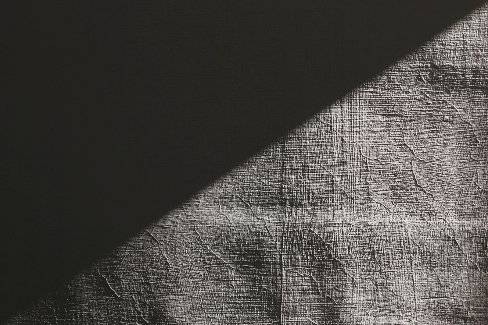 A diagonal band of light across a rough textured wall
