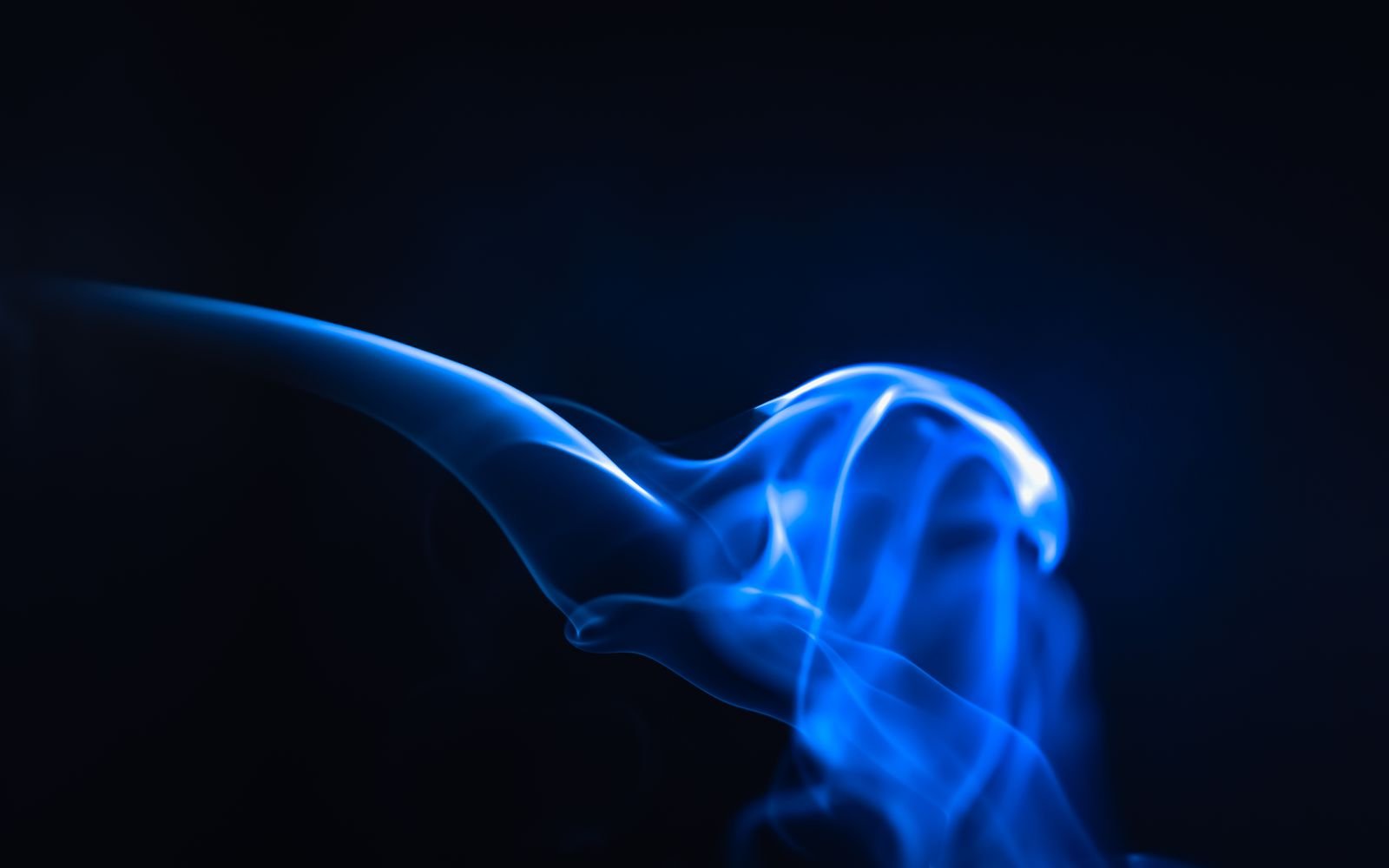 Blue-lit smoke curling through a dark space