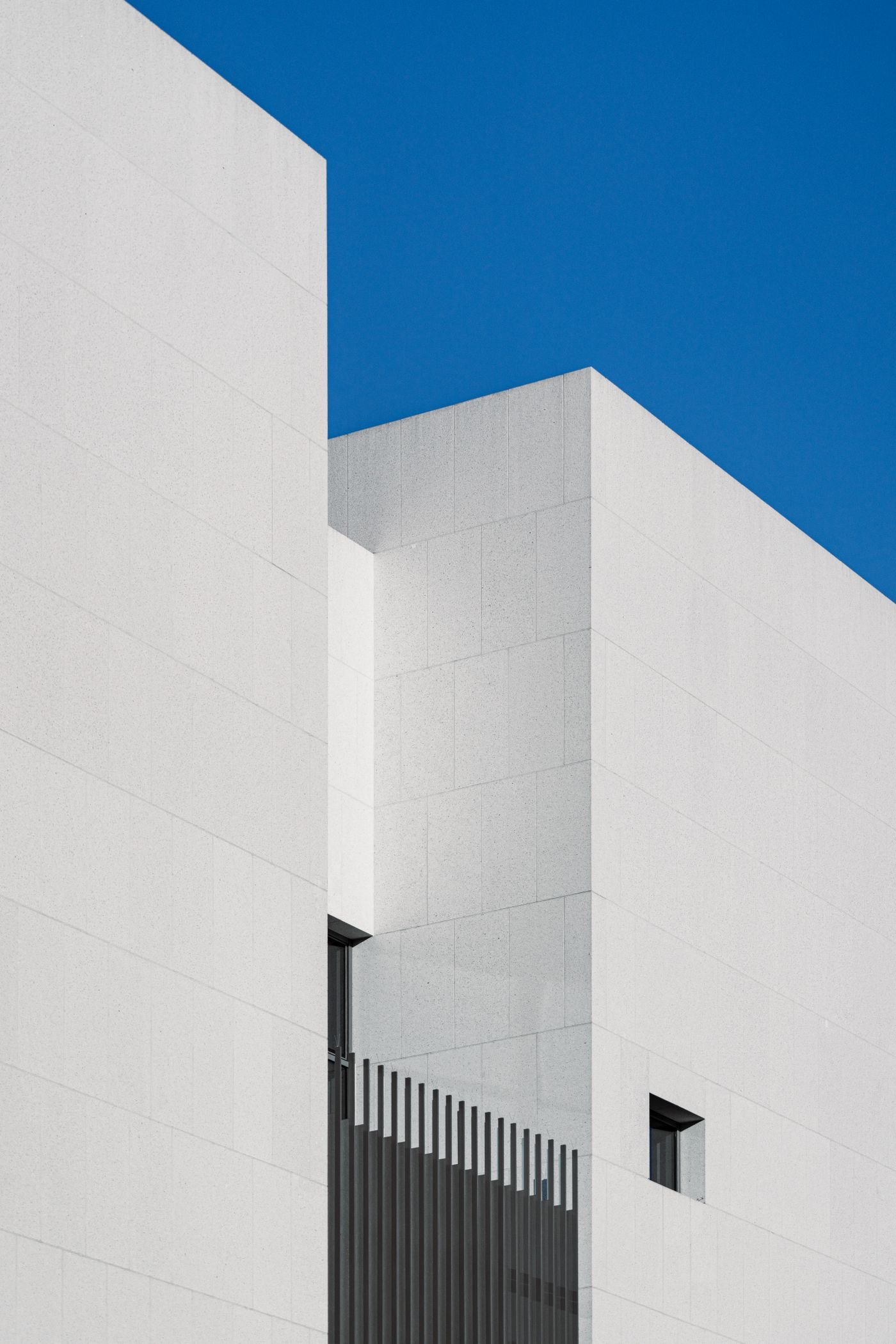 A white minimalist building corner against a clear blue sky