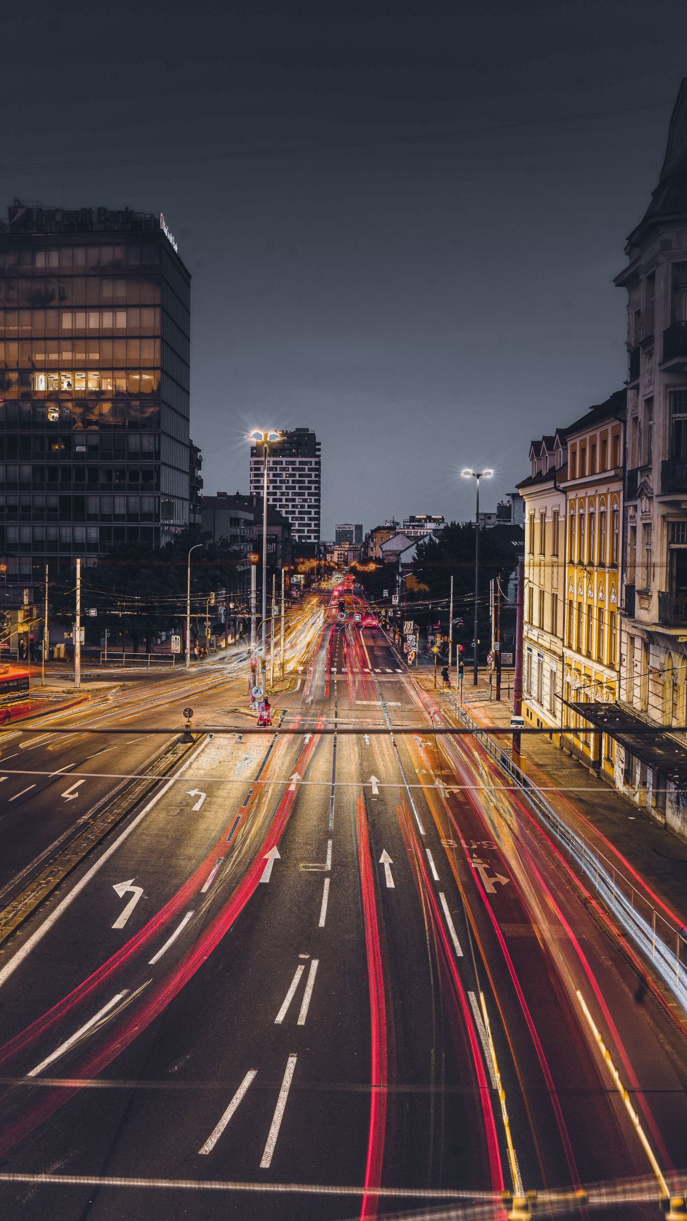 Long-exposure light trails running down a city street at night