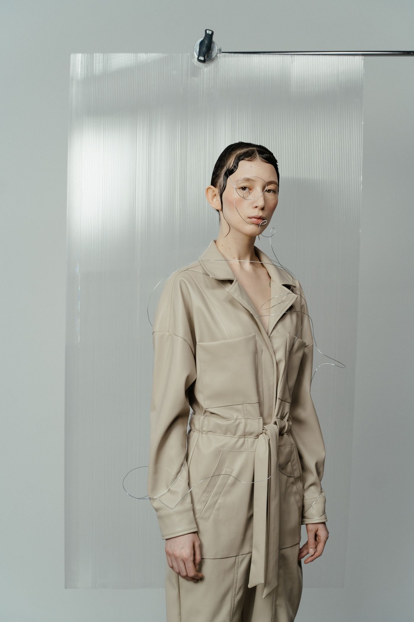 A person in a beige tailored jumpsuit in a bright studio
