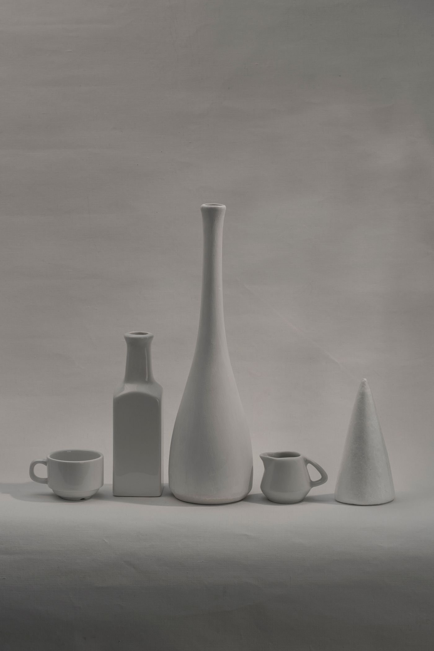 A still life of pale ceramic vessels in soft grey light