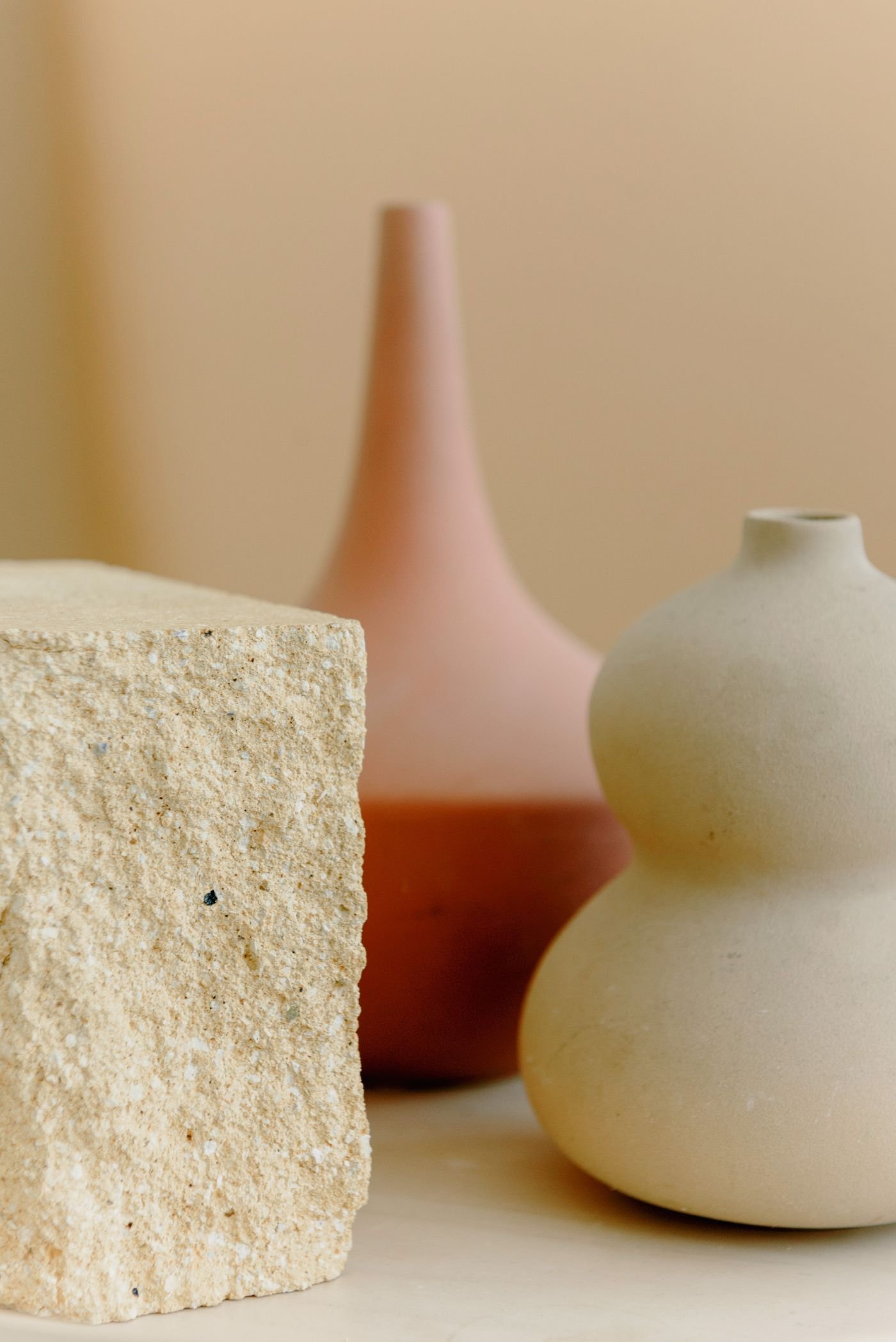 A sculptural vase beside a block of raw stone