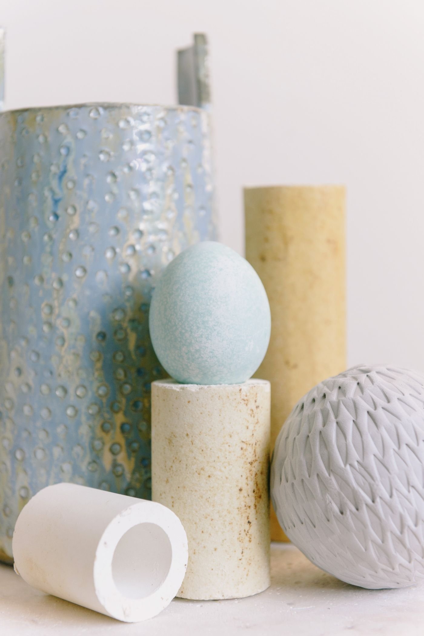 A grouping of textured ceramic objects on a pale surface