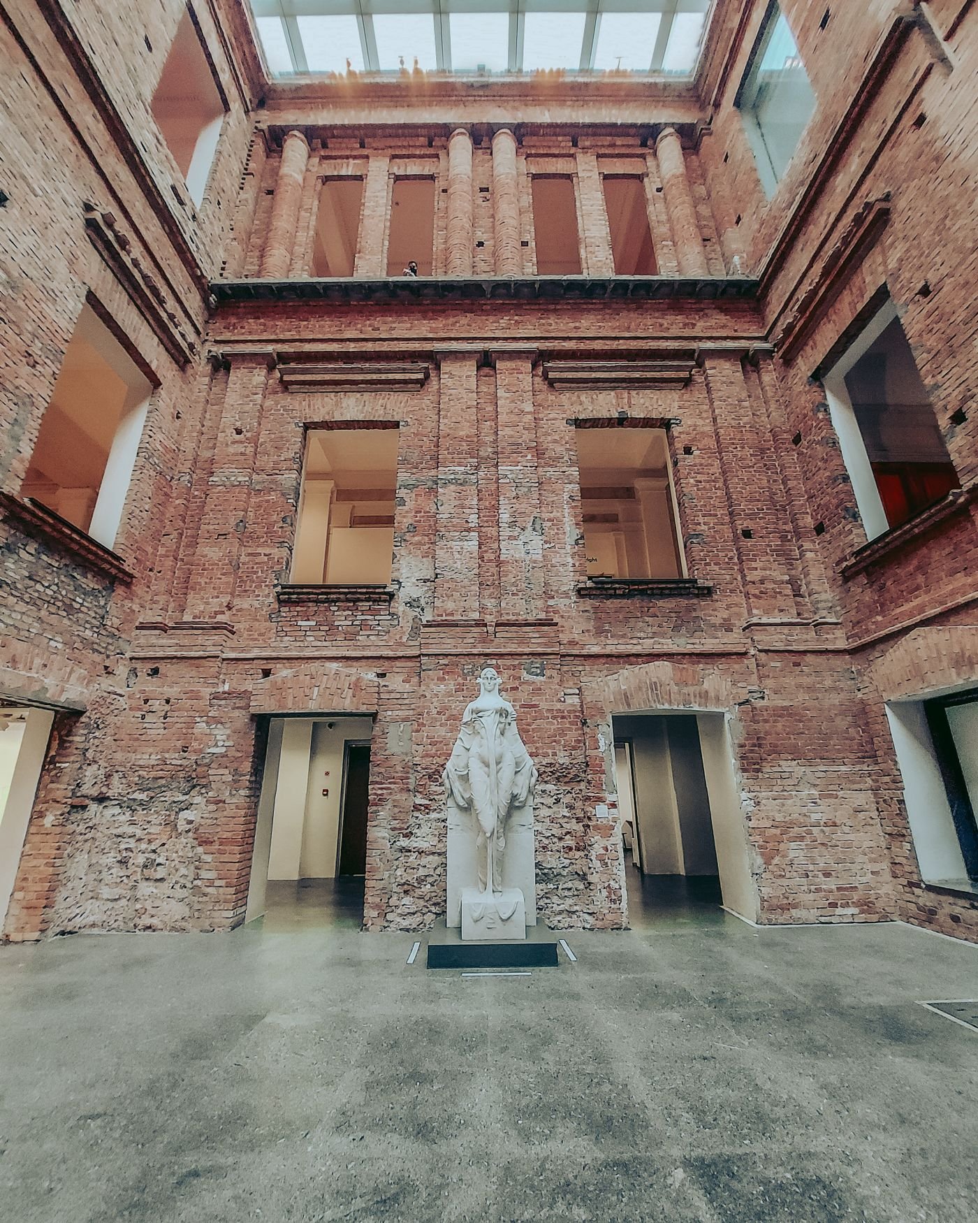A tall brick atrium with a skylight above a central statue