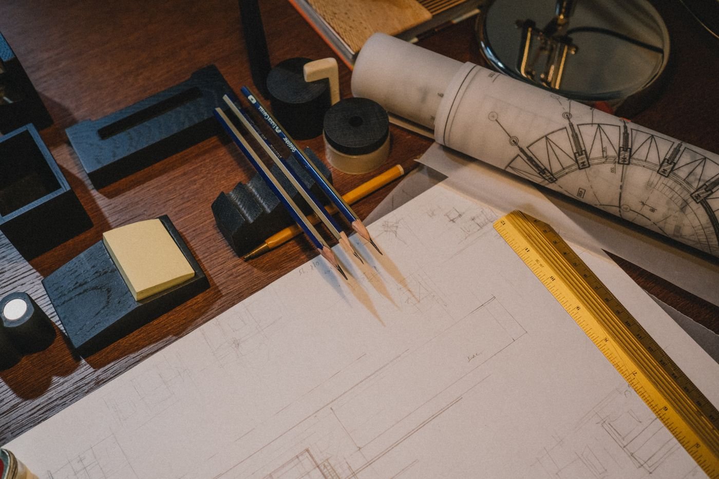 Drafting tools, rolled drawings and notebooks on a desk