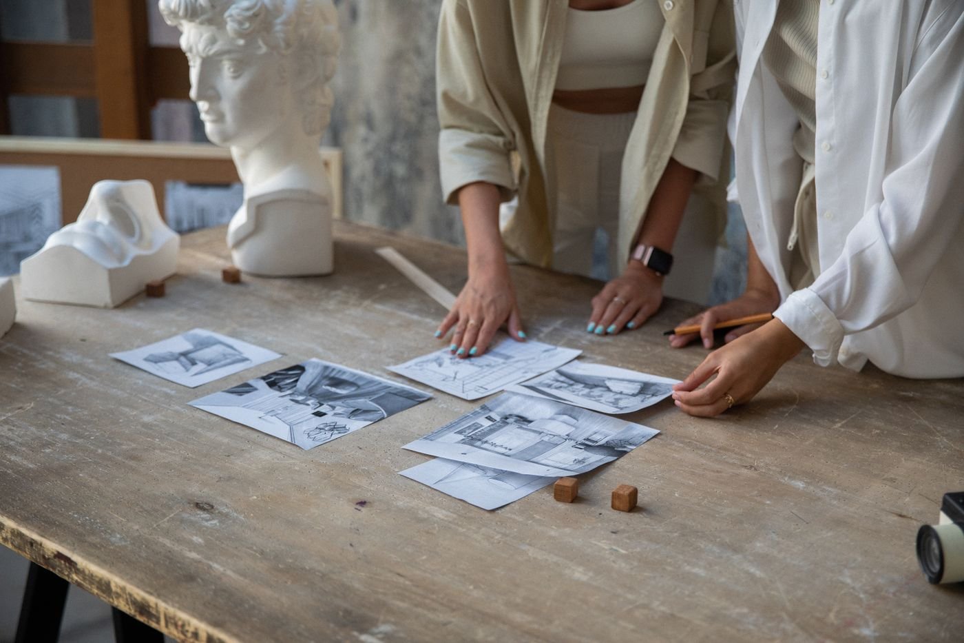Hands arranging printed photographs across a studio table