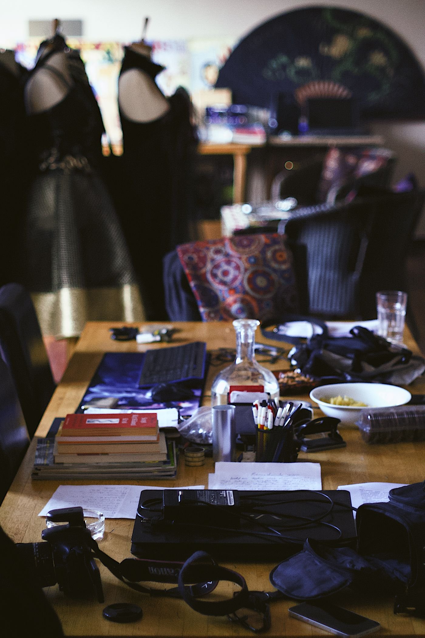 A workshop table lit by a desk lamp, covered in tools and materials