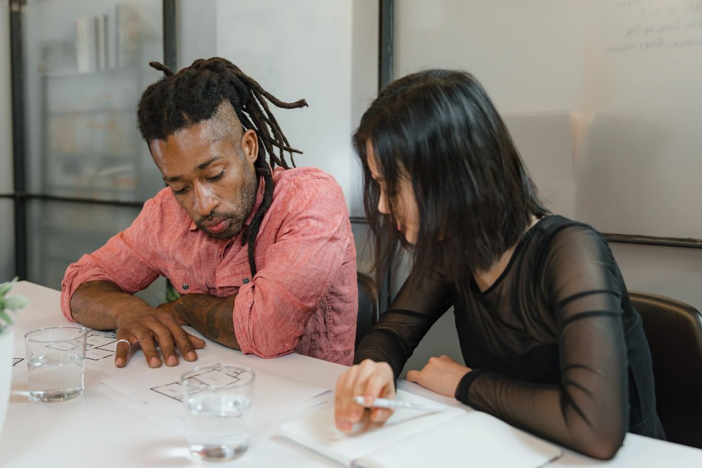 Two people talking across a table in a bright meeting room