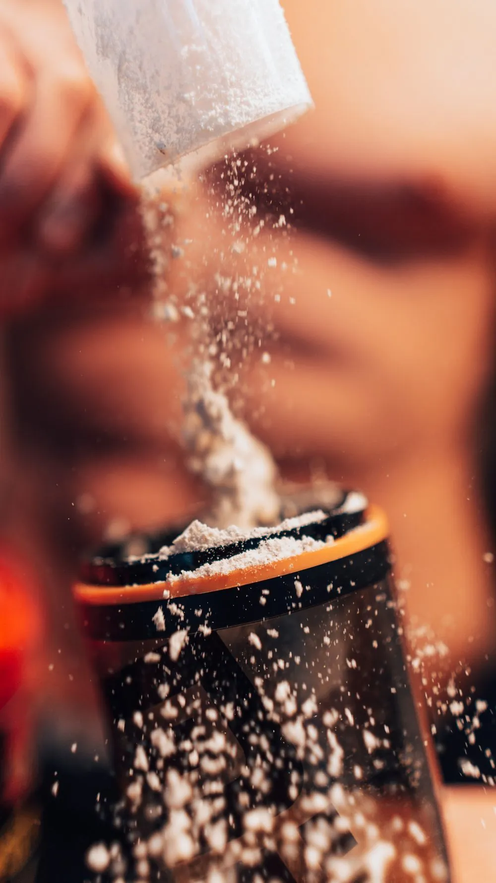 Scoop of protein powder being mixed into a shaker