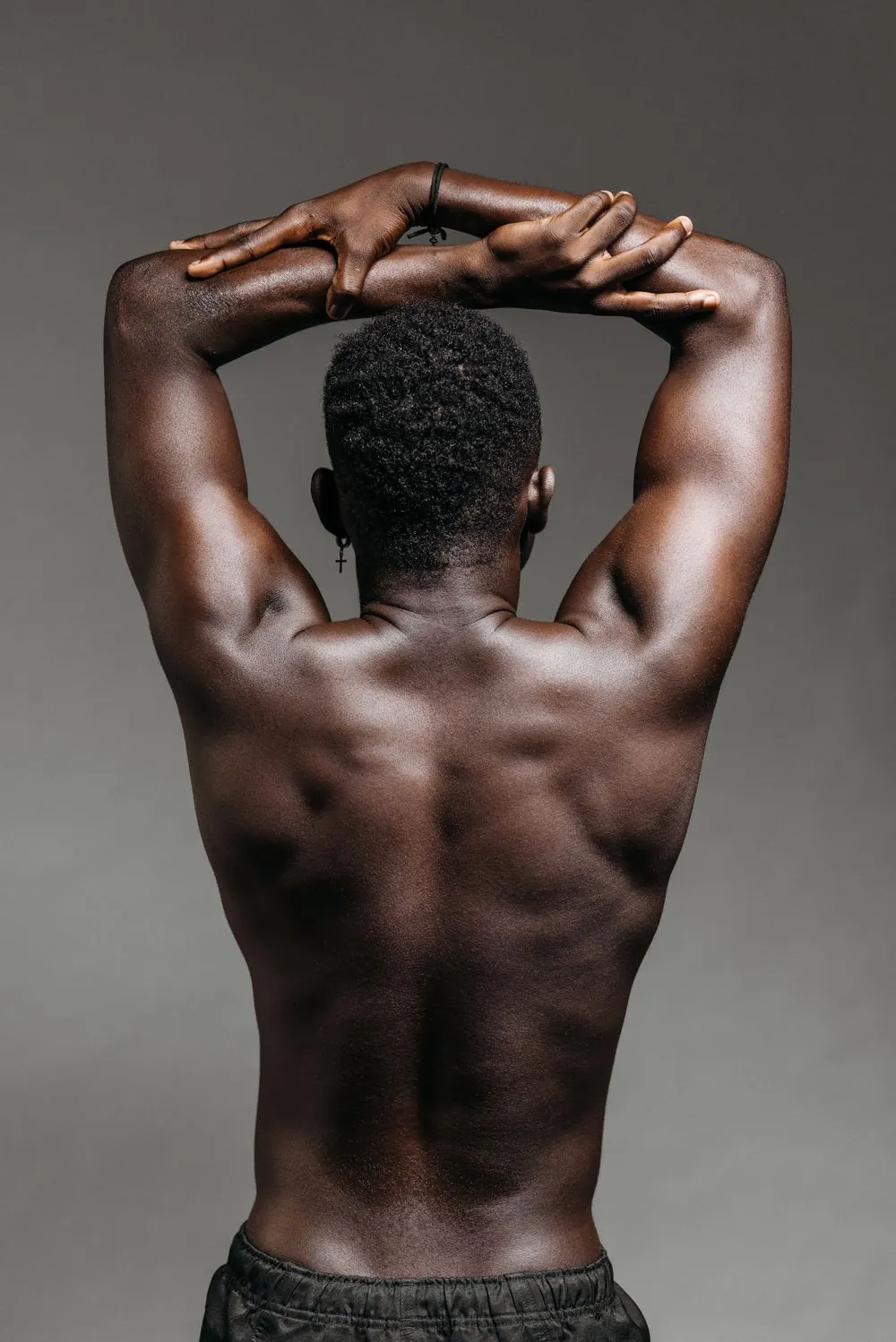 Back view of an athlete stretching against a grey backdrop