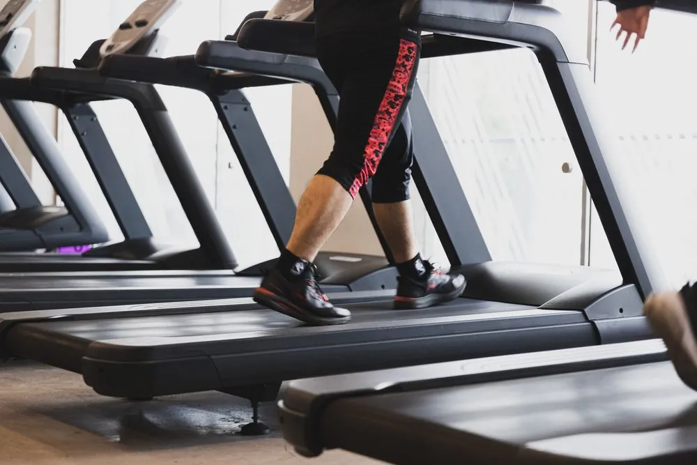 Legs of a runner mid-stride on a treadmill belt