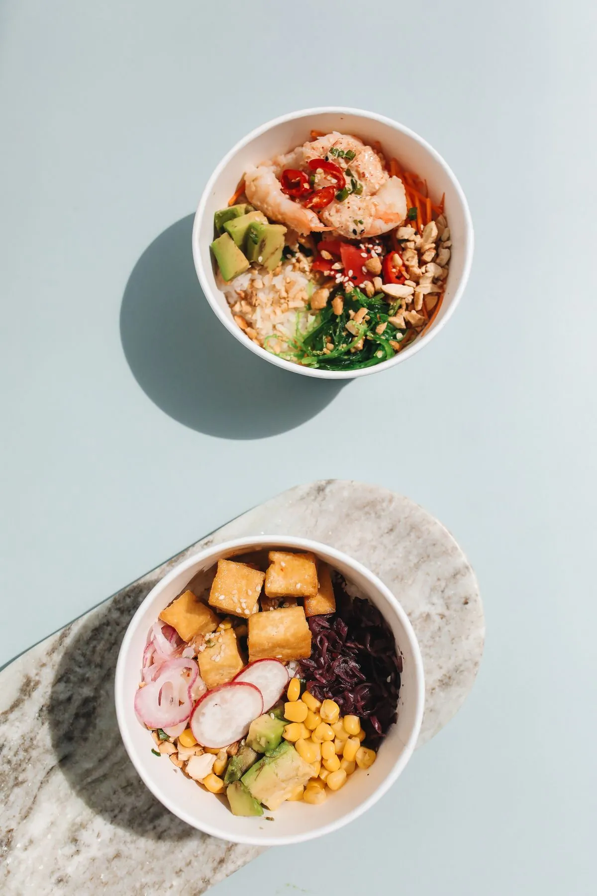 Two poke bowls with tofu, avocado and rice