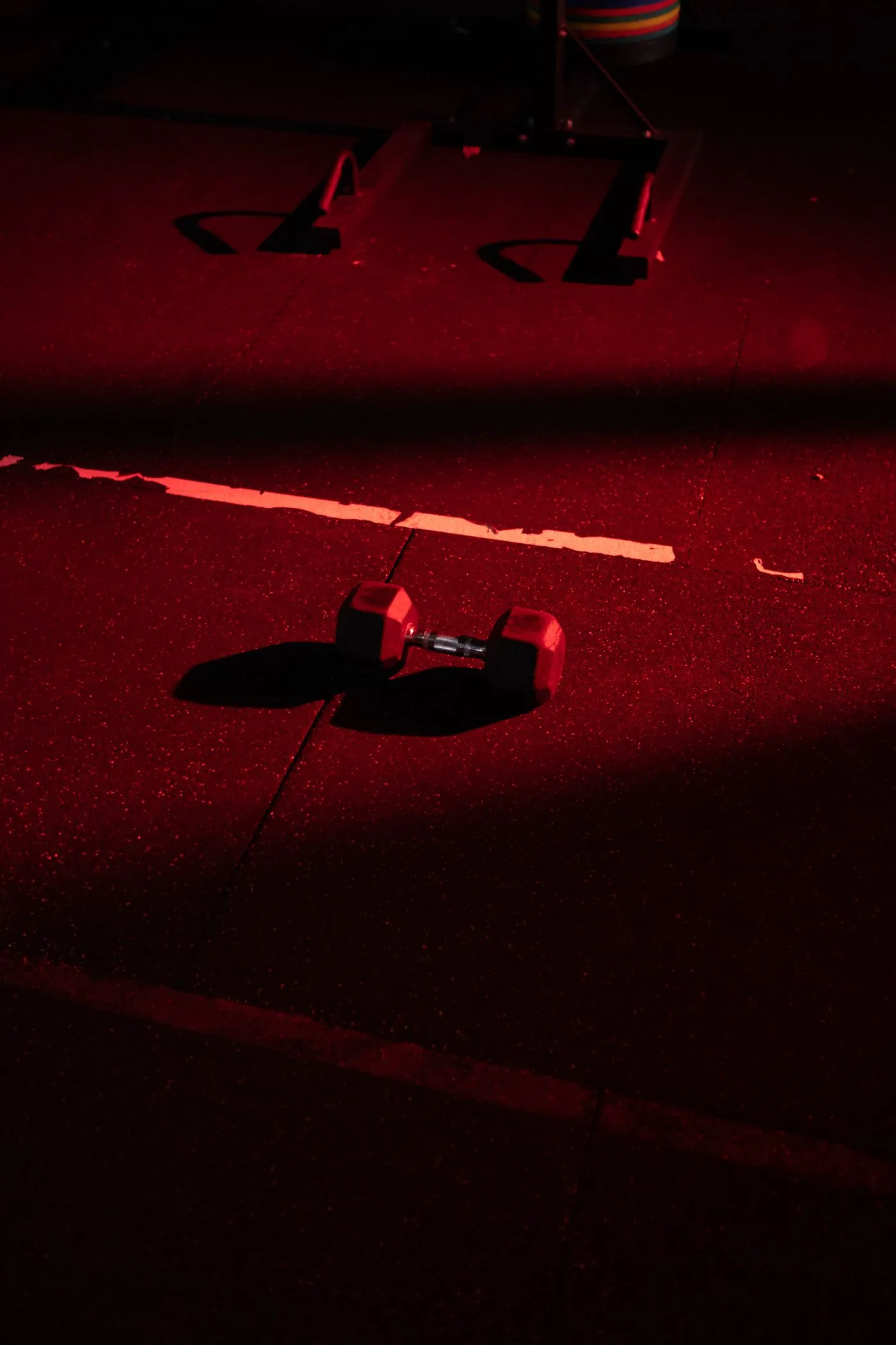 Single dumbbell on the floor under a red light wash