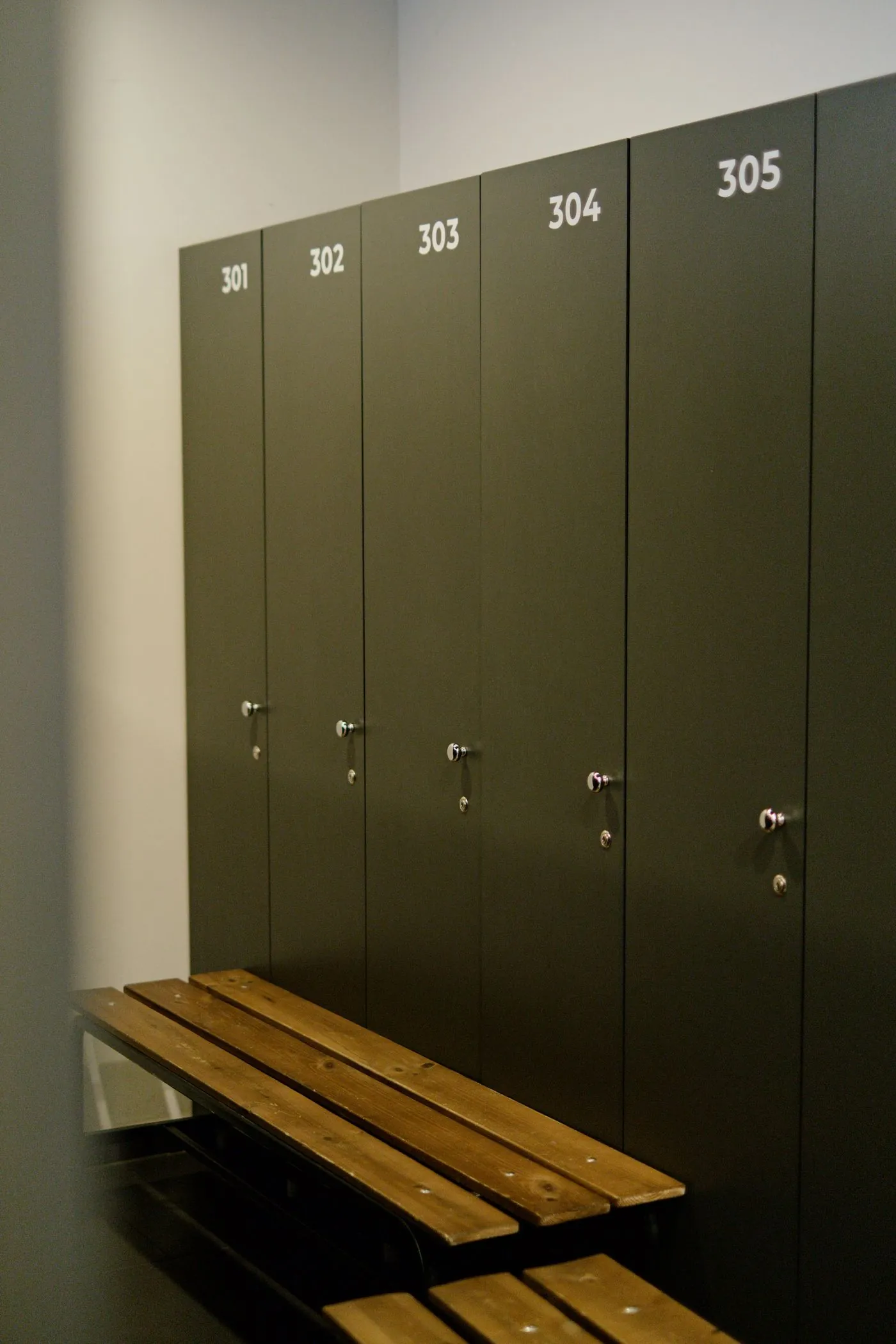 Row of olive-green lockers above a wooden bench
