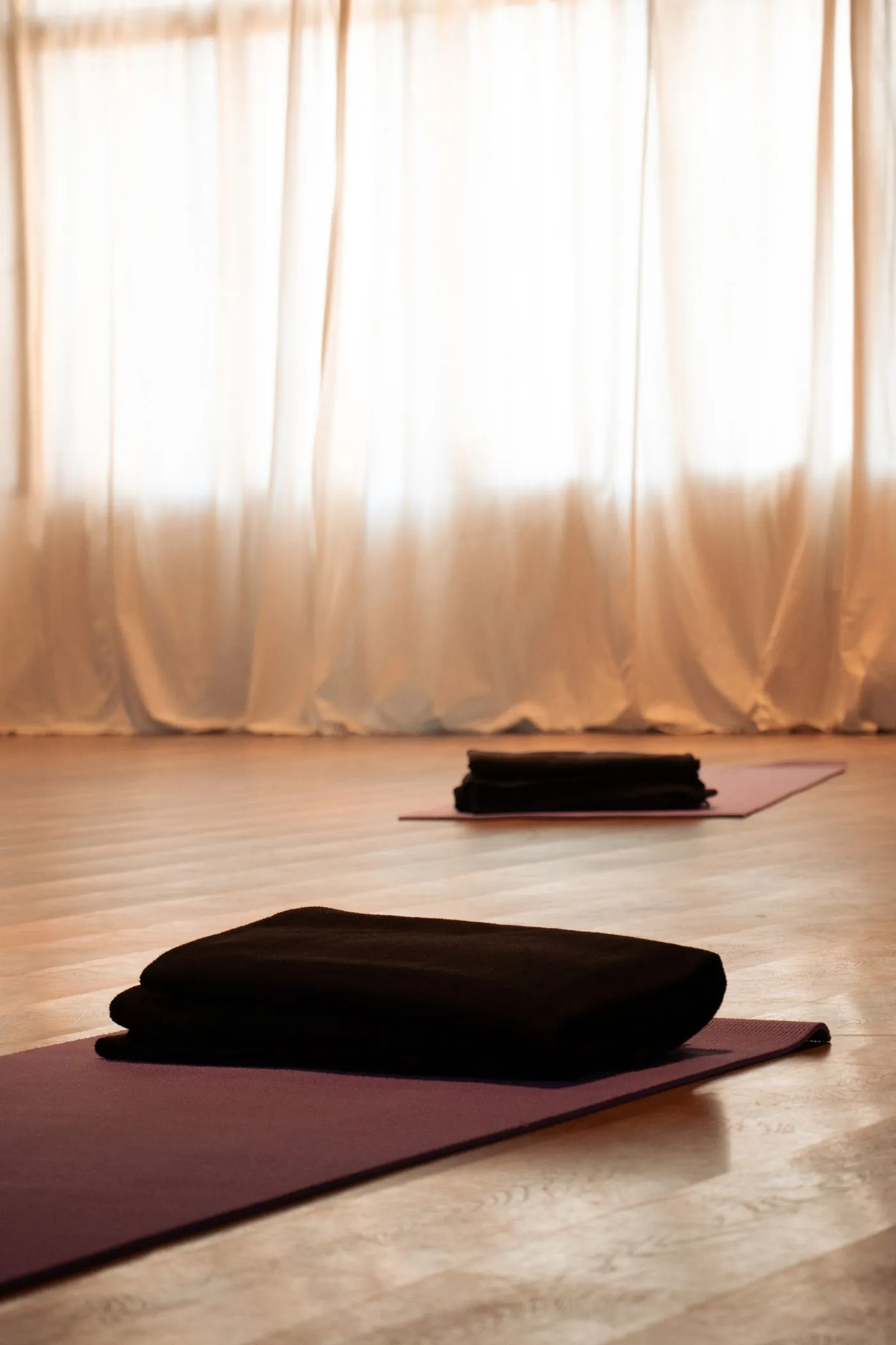 Quiet studio corner with a rolled mat and linen curtain