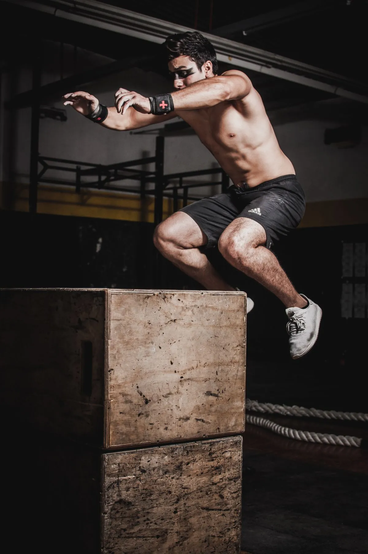 Athlete mid-air over a plyometric box in a dark gym