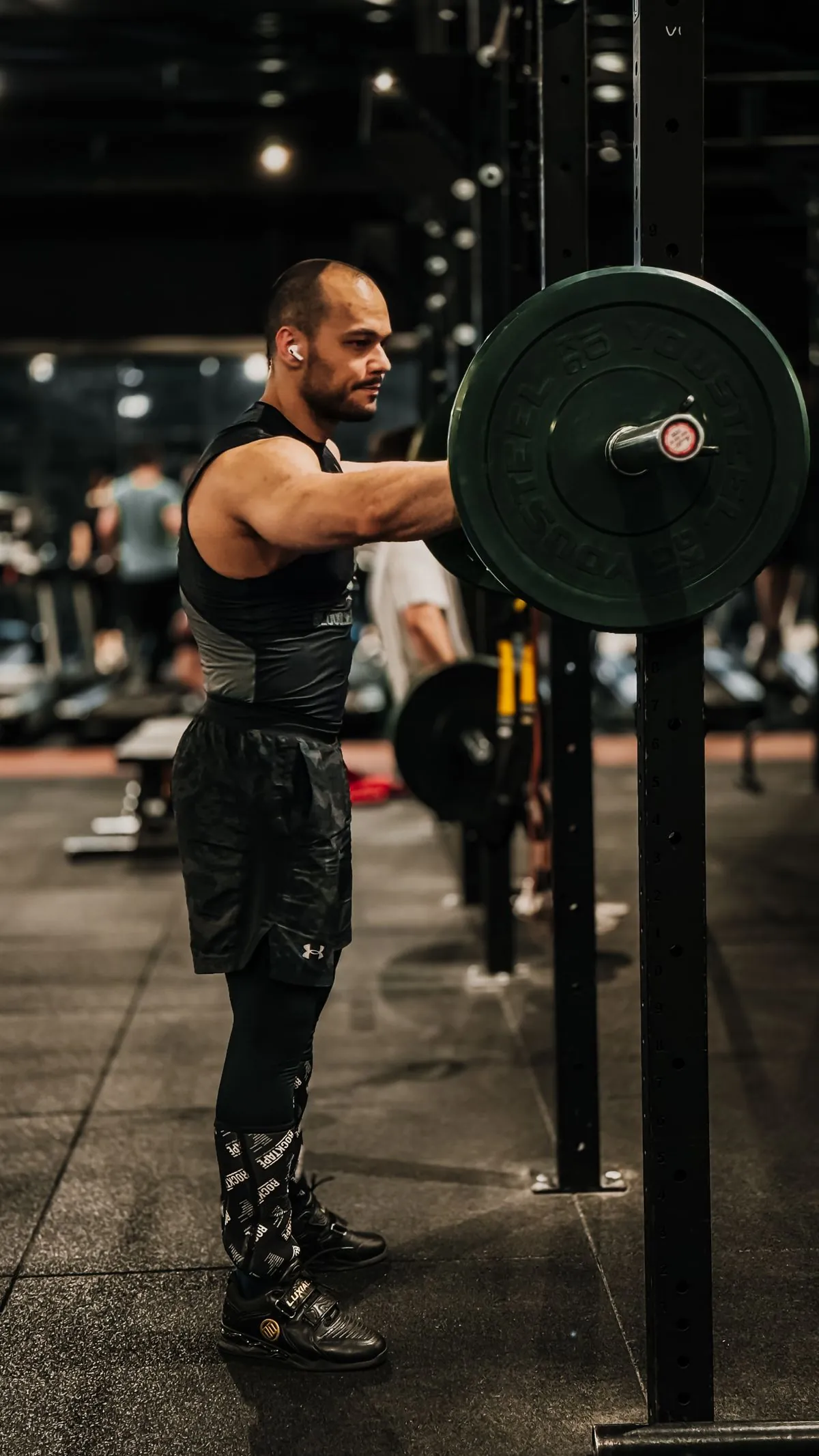 Lifter driving a loaded barbell overhead in a dim industrial gym