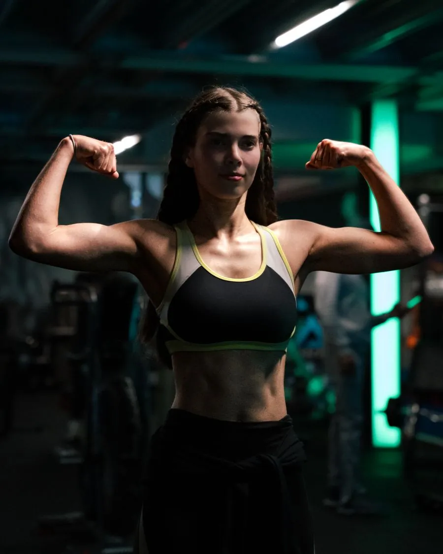 Athlete flexing in a teal-lit gym