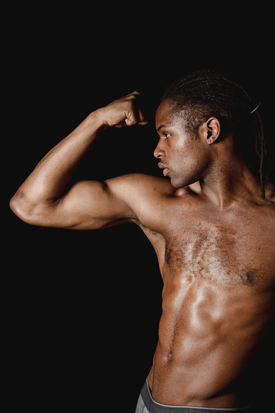 Athlete flexing a bicep in a dark studio