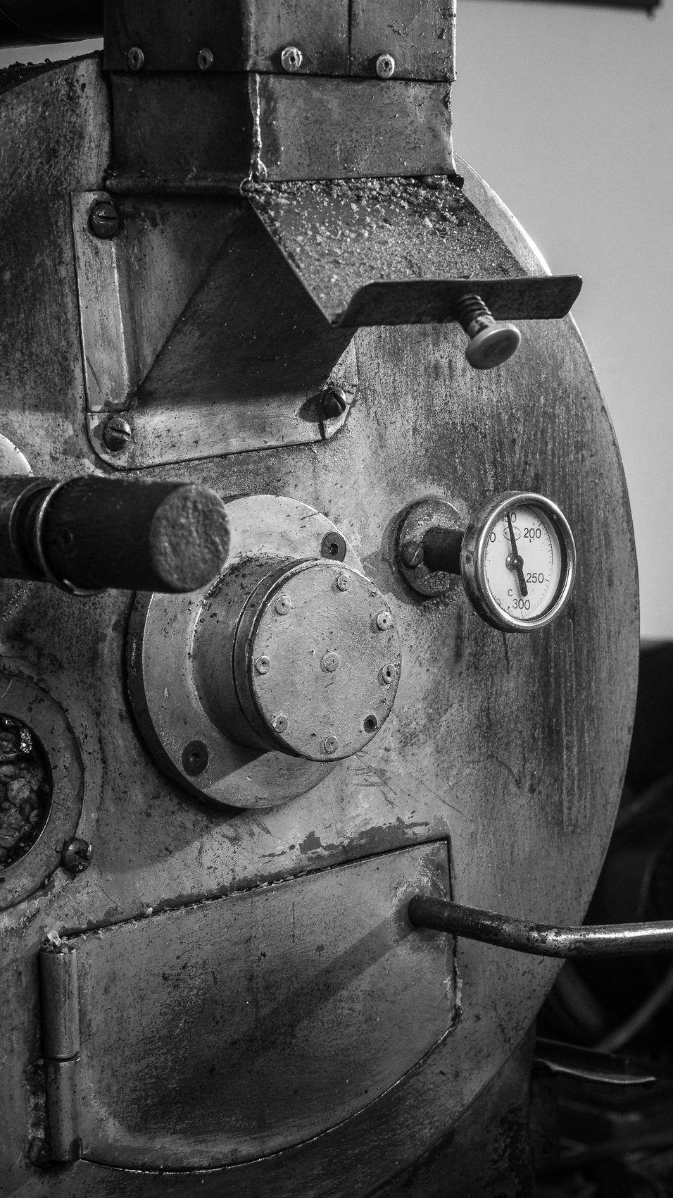 Monochrome close-up of a heavy industrial roaster drum face