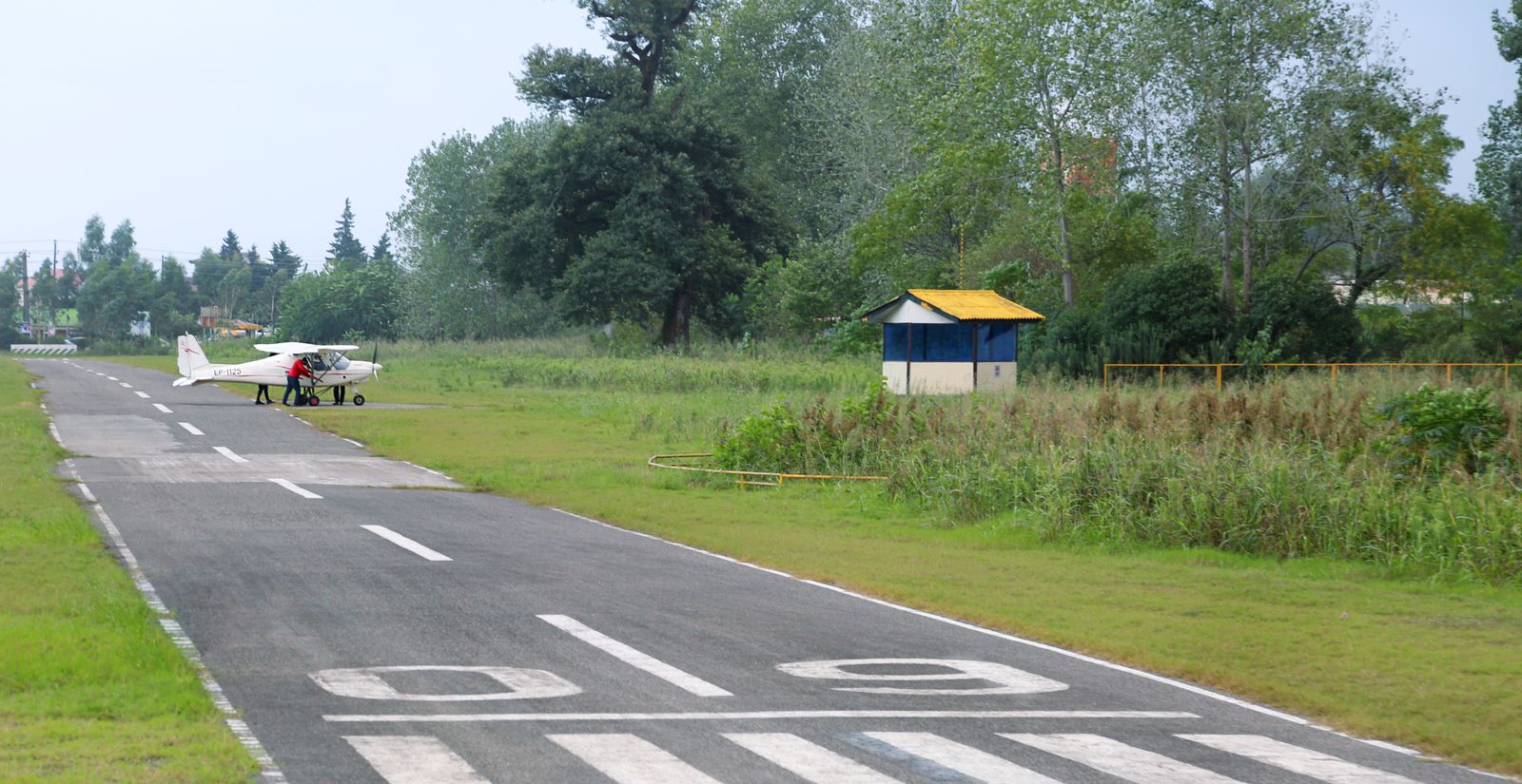 A light aircraft taxiing on a grass-lined private airstrip
