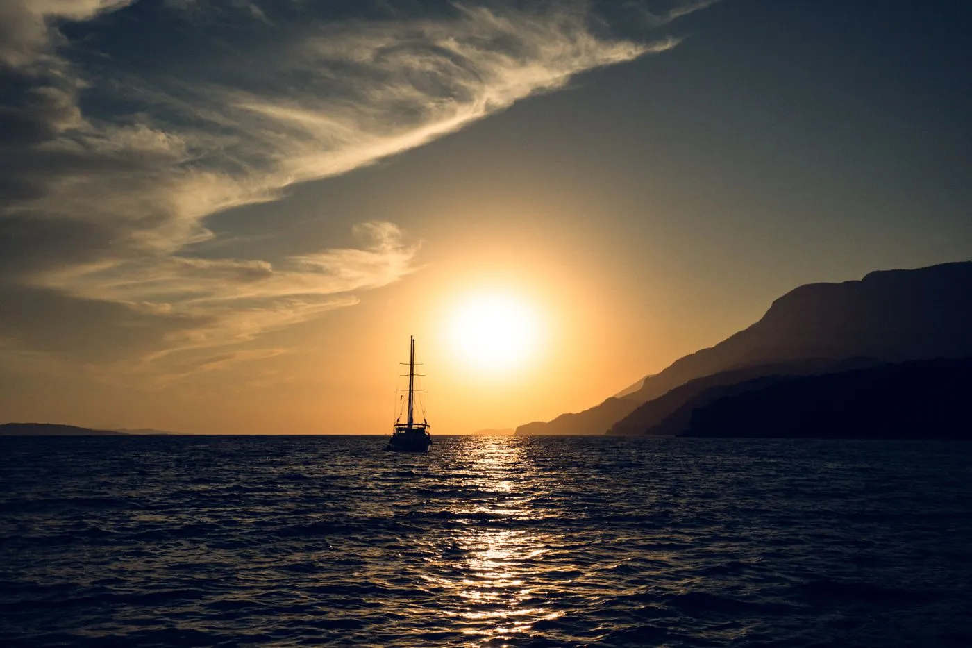 A sailing yacht silhouetted against a golden sunset