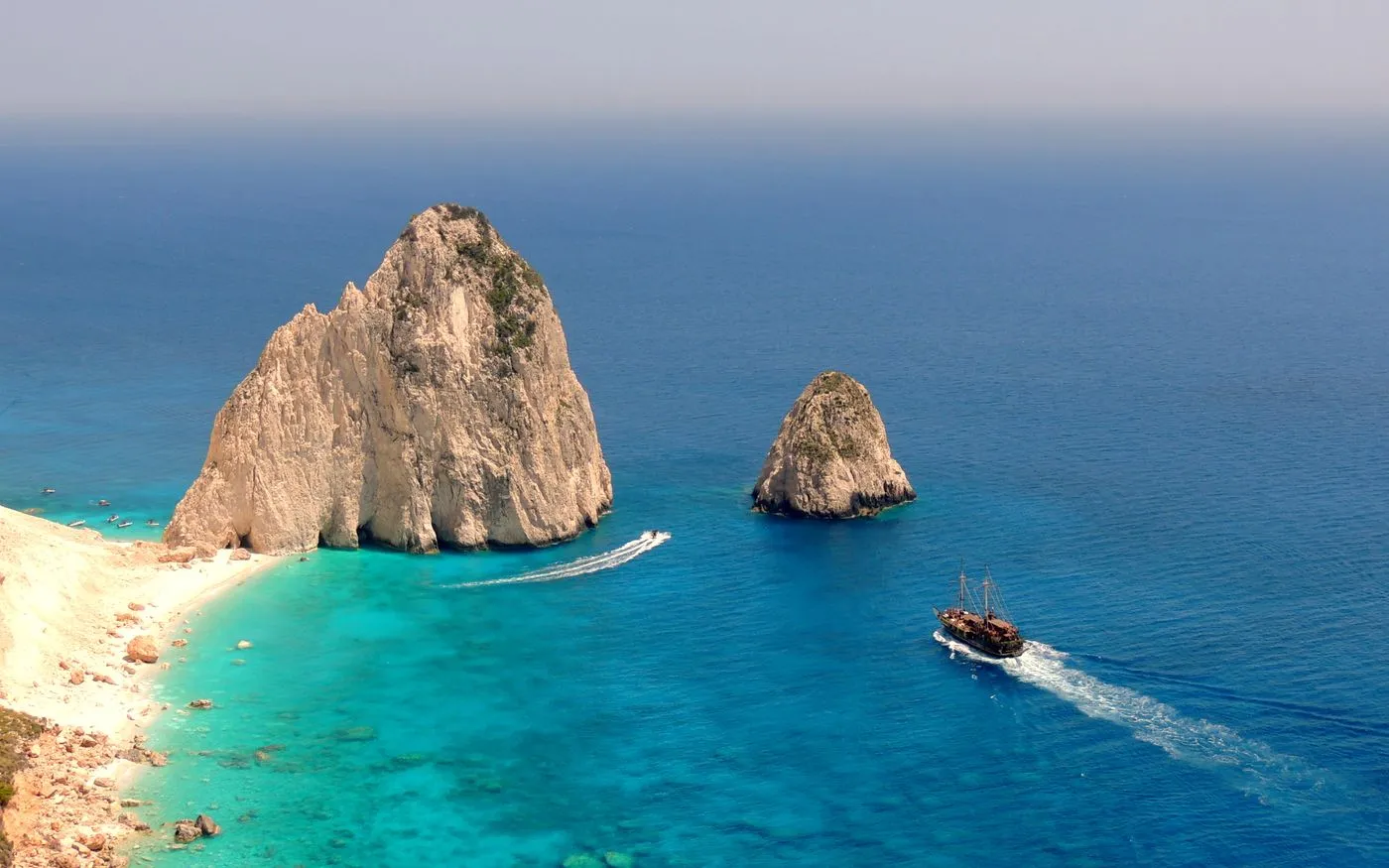 Boat on turquoise water beside pale rock formations
