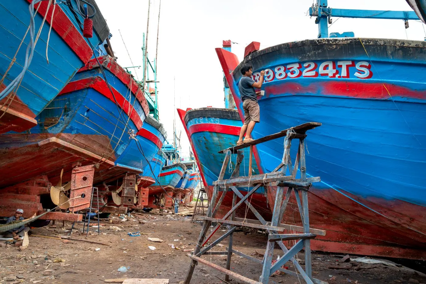 A shipwright working on a hull from scaffolding