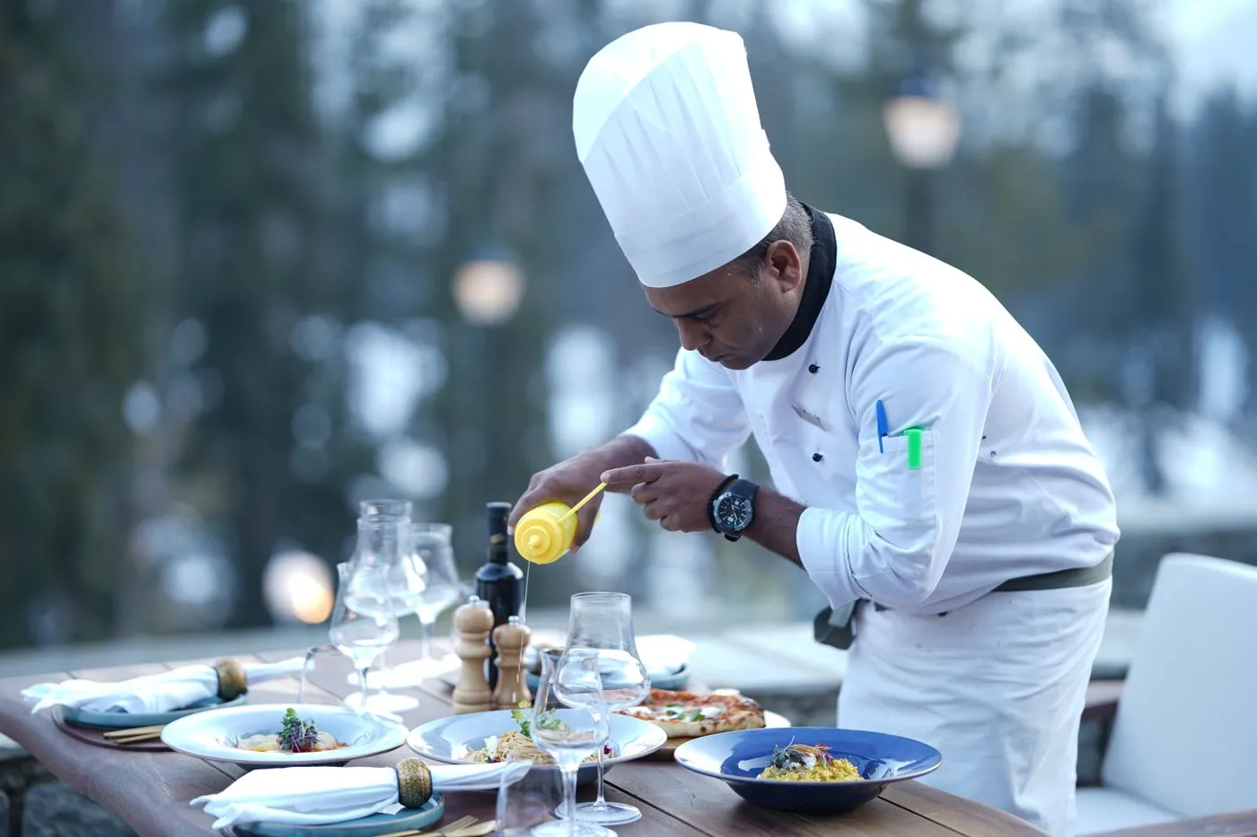 A chef preparing dishes for a table set outdoors