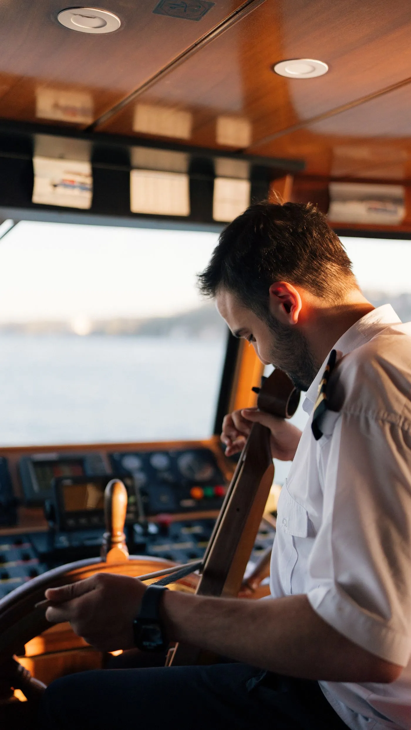 Uniformed captain steering a vessel at golden hour