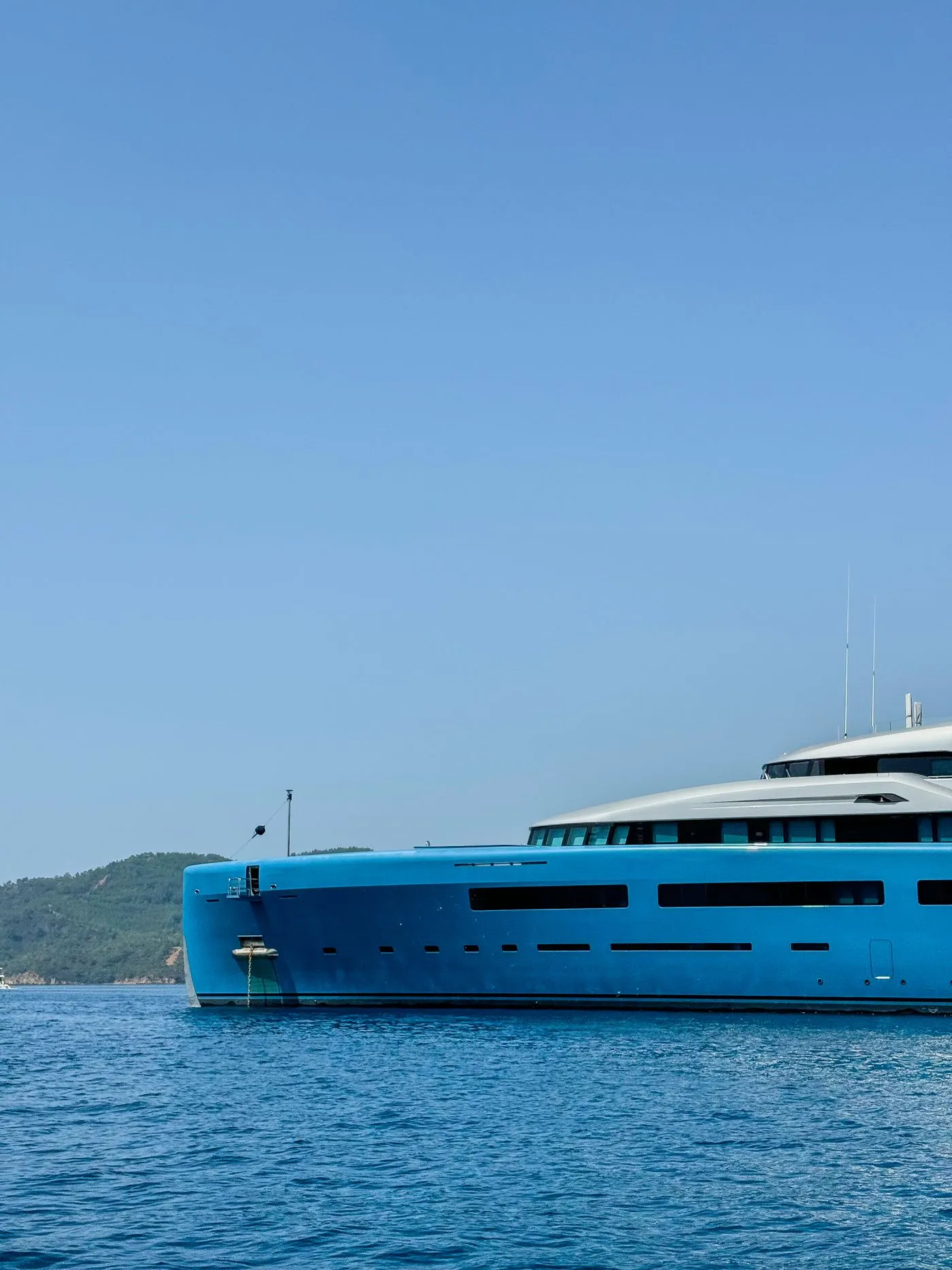 Blue-hulled yacht cruising clear water in bright sun