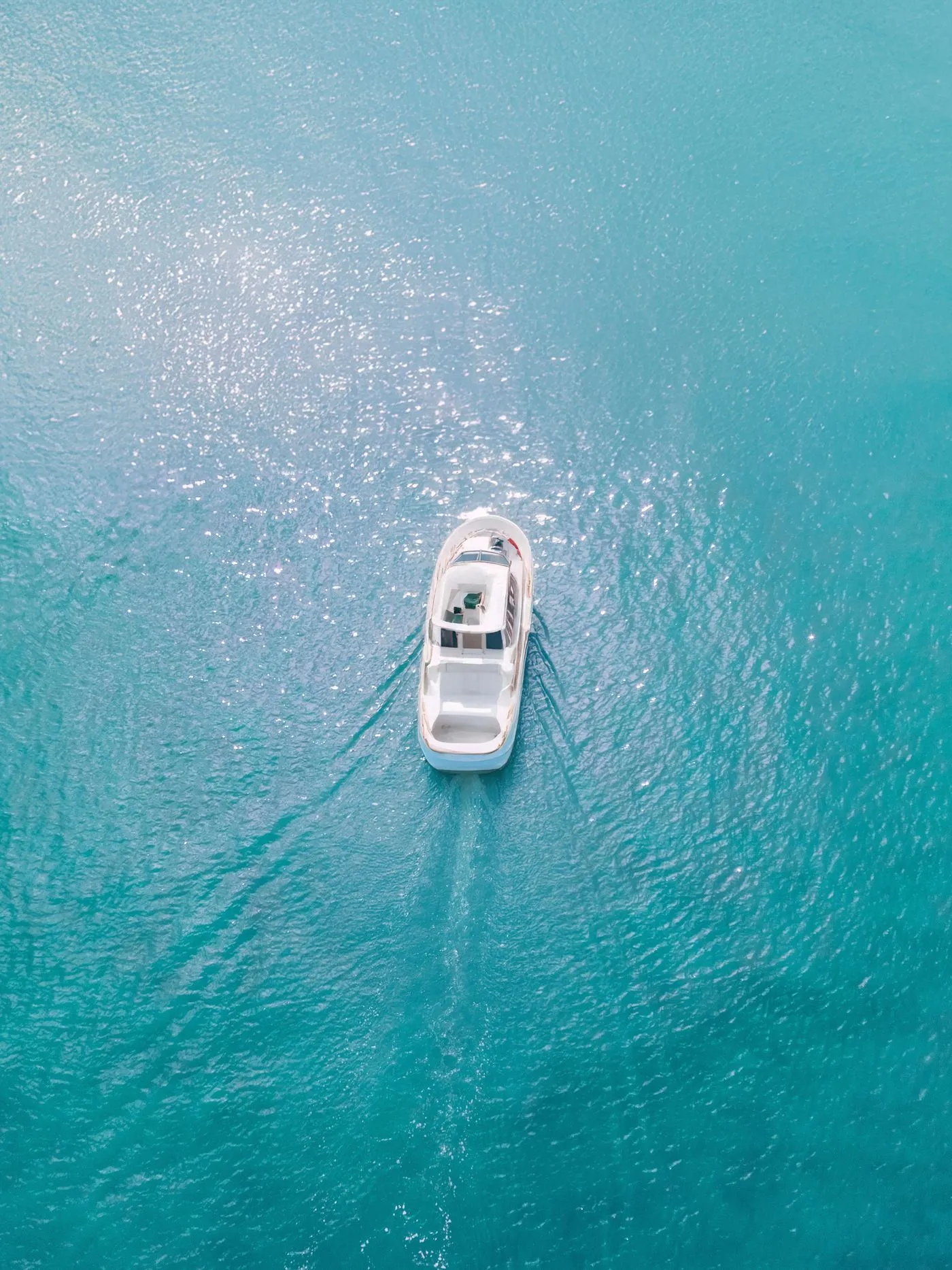 Aerial view of a white motor yacht crossing bright turquoise water